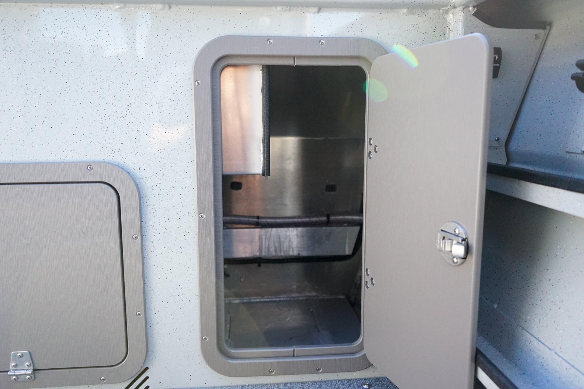 Open storage compartment on a 2026 Weldcraft 210 Revolution boat, showcasing interior space.
