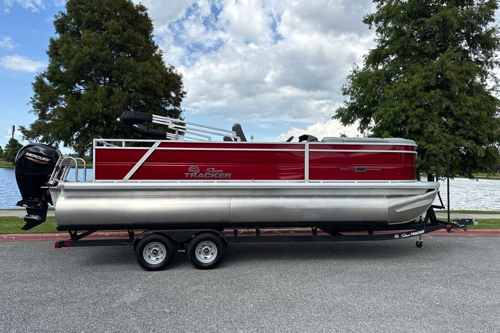 2026 Sun Tracker Party Barge 22 RF DLX pontoon boat on trailer by a lake.