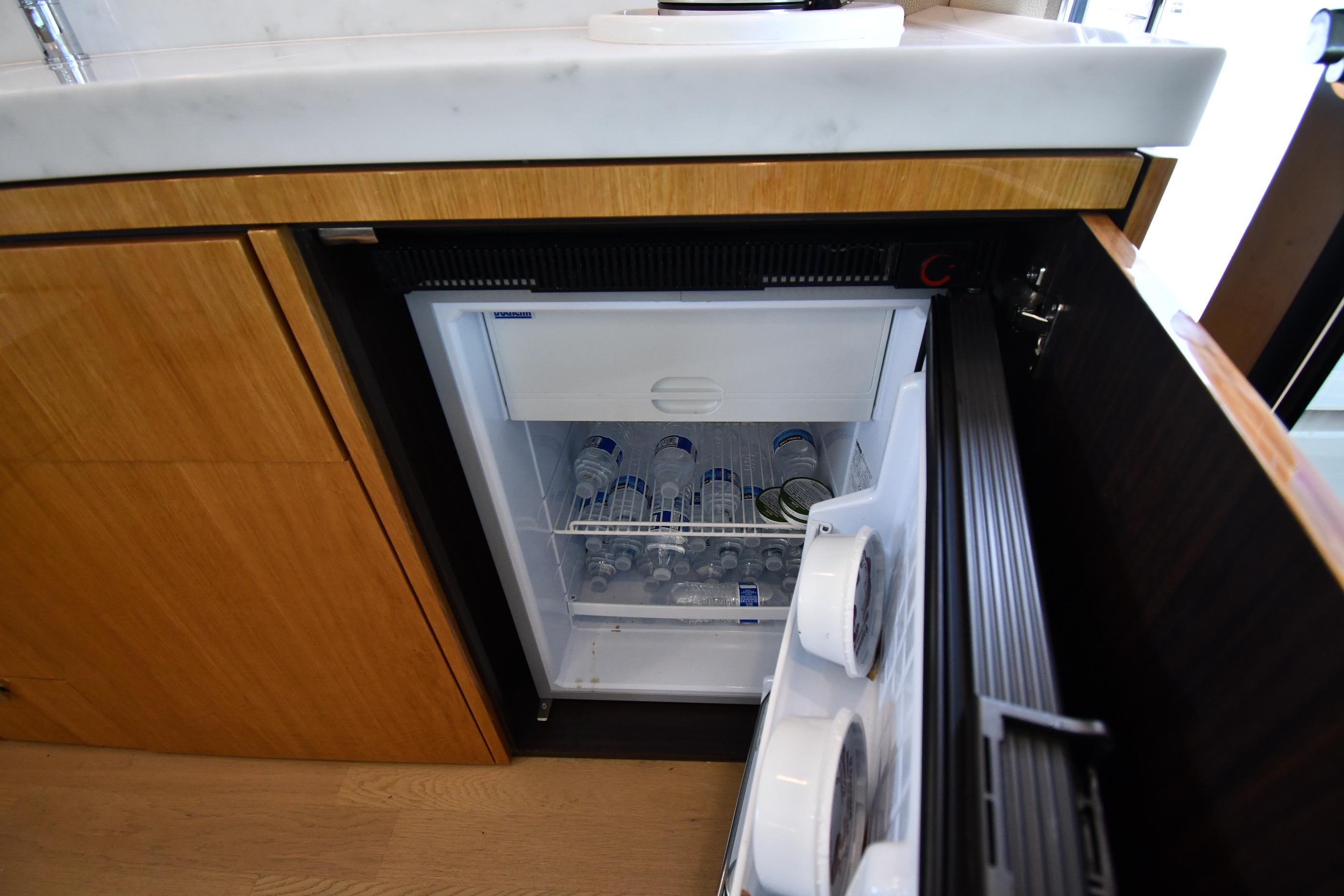 Mini fridge in 2024 Fairline G50 Targa yacht kitchen, stocked with bottled water.