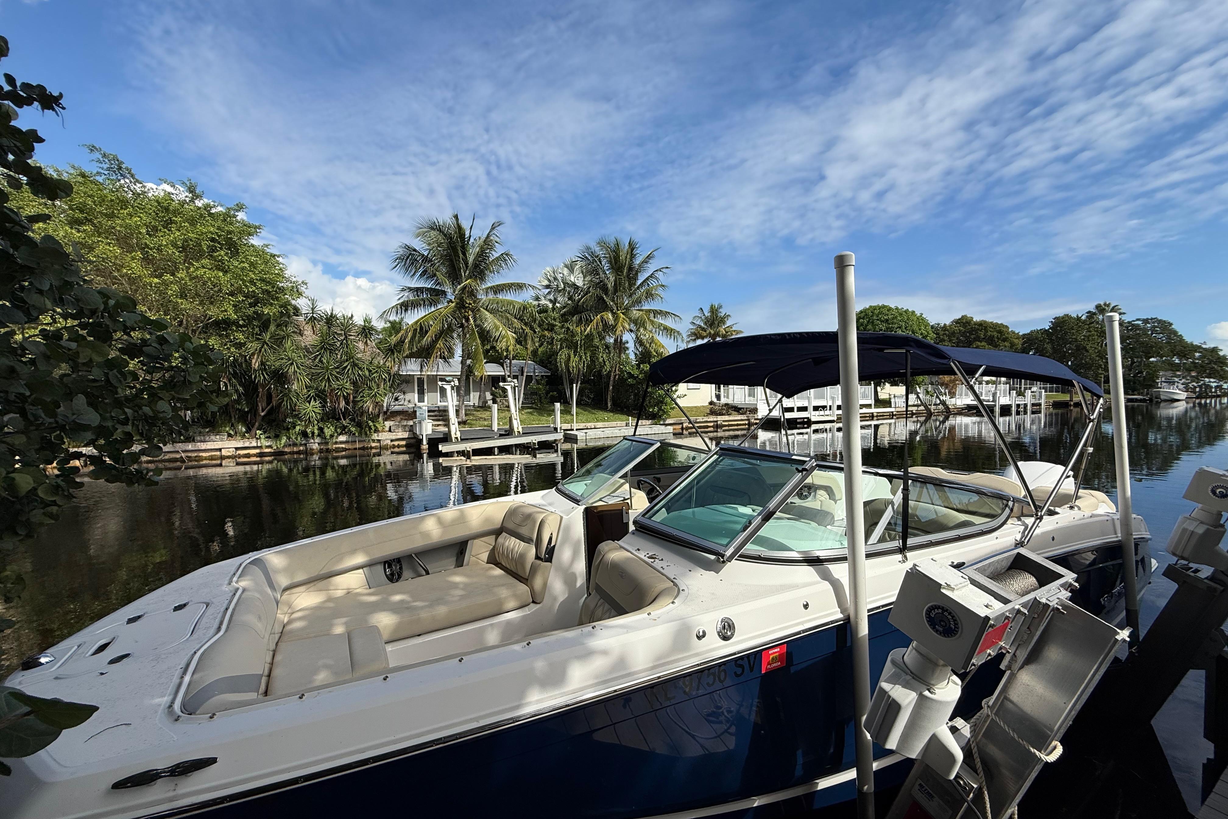 2021 Regal 26 OBX boat docked by a scenic waterfront with palm trees.