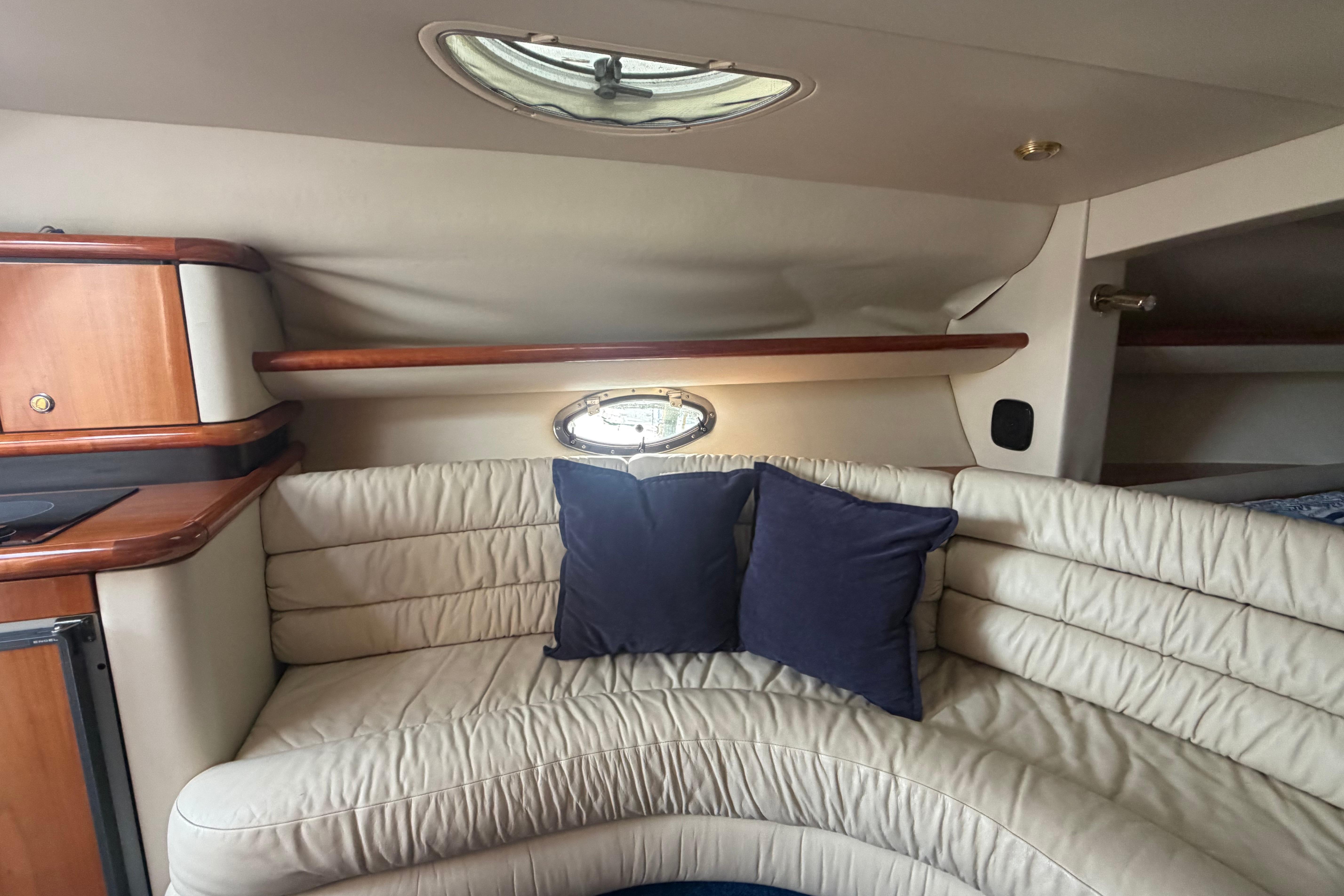 Interior of 2000 Sunseeker Superhawk 34 yacht with cream leather seating and blue cushions.