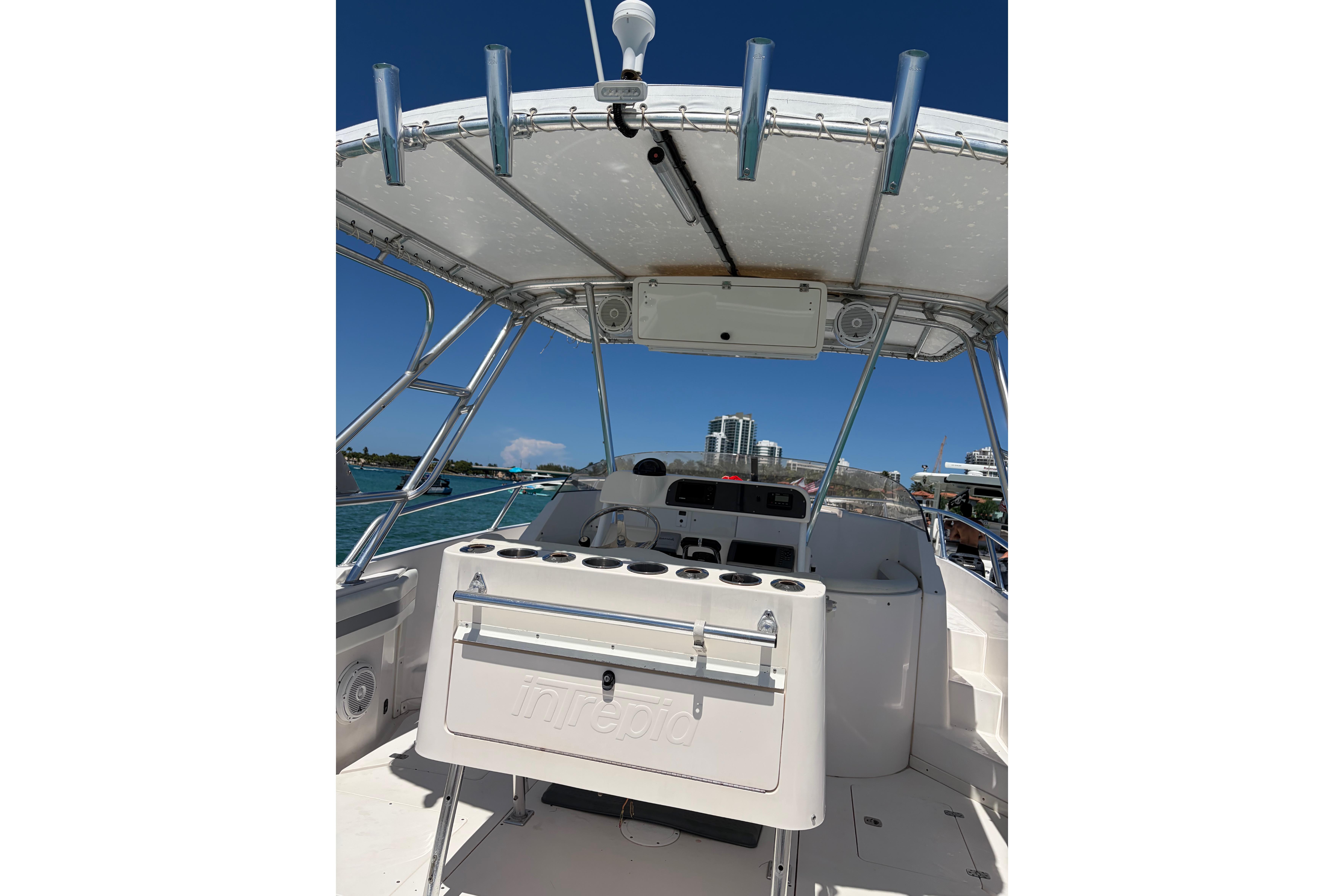 1998 Intrepid 339 Walkaround boat interior with rod holders and helm, under clear blue sky.