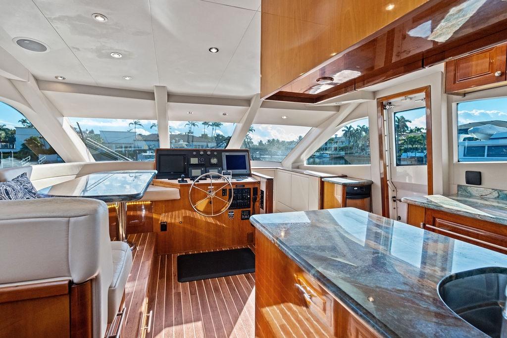 Luxurious interior of 2008 Hatteras 64 Motor Yacht with polished wood and modern helm.