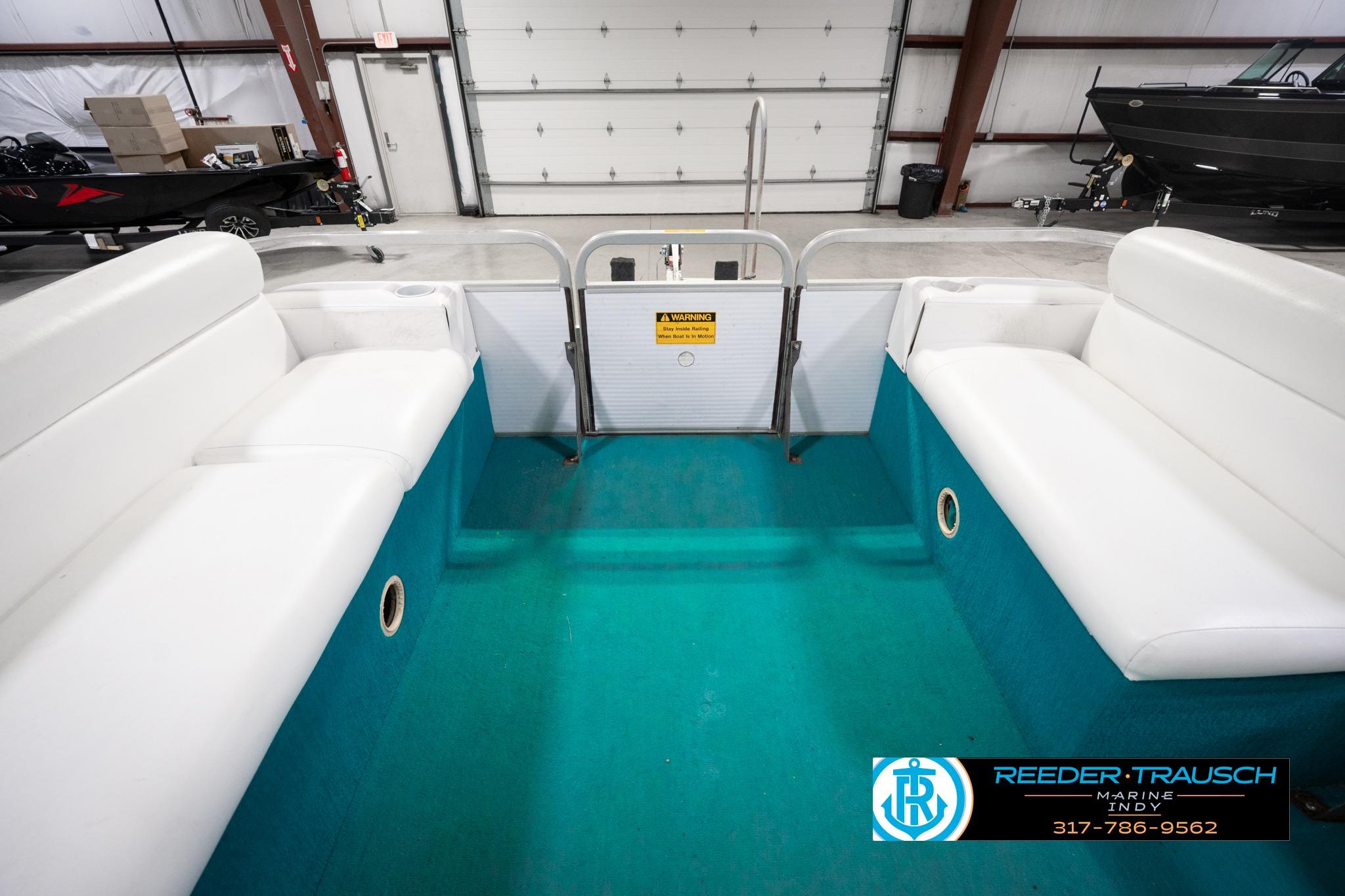 Interior of a 1992 Godfrey Sweetwater boat with white seating and teal flooring.