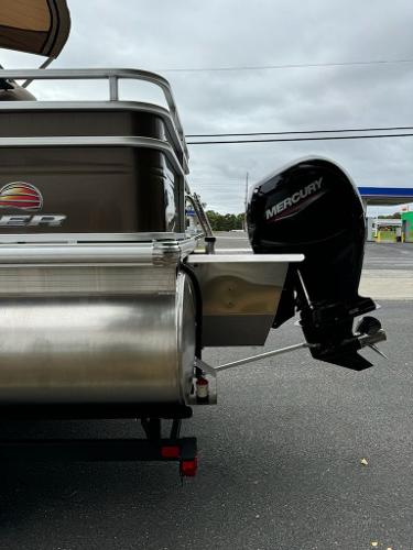 2025 Sun Tracker SportFish 22 XP3 with Mercury outboard motor, parked on asphalt.