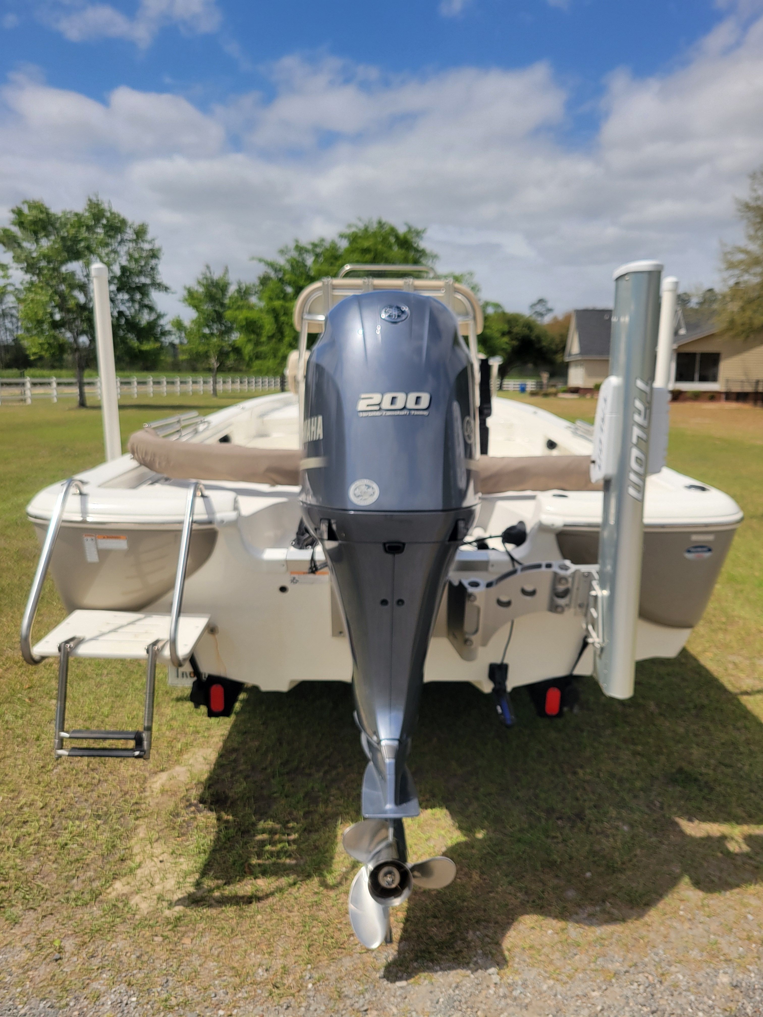 A 2017 NauticStar 2200 Sport boat on a trailer in a grassy area.