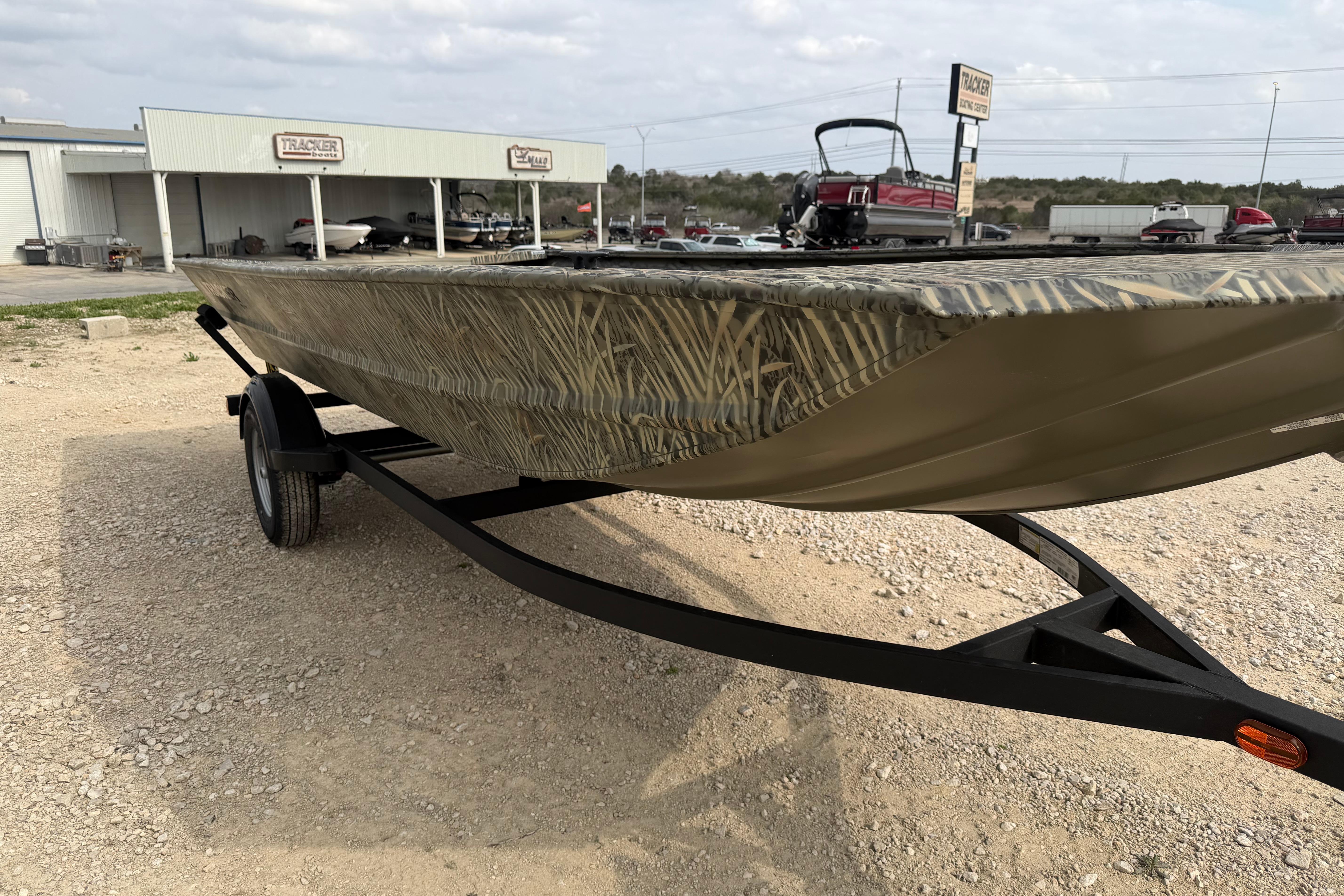 2026 Tracker Grizzly 1754 Utility boat on trailer, parked outside dealership.