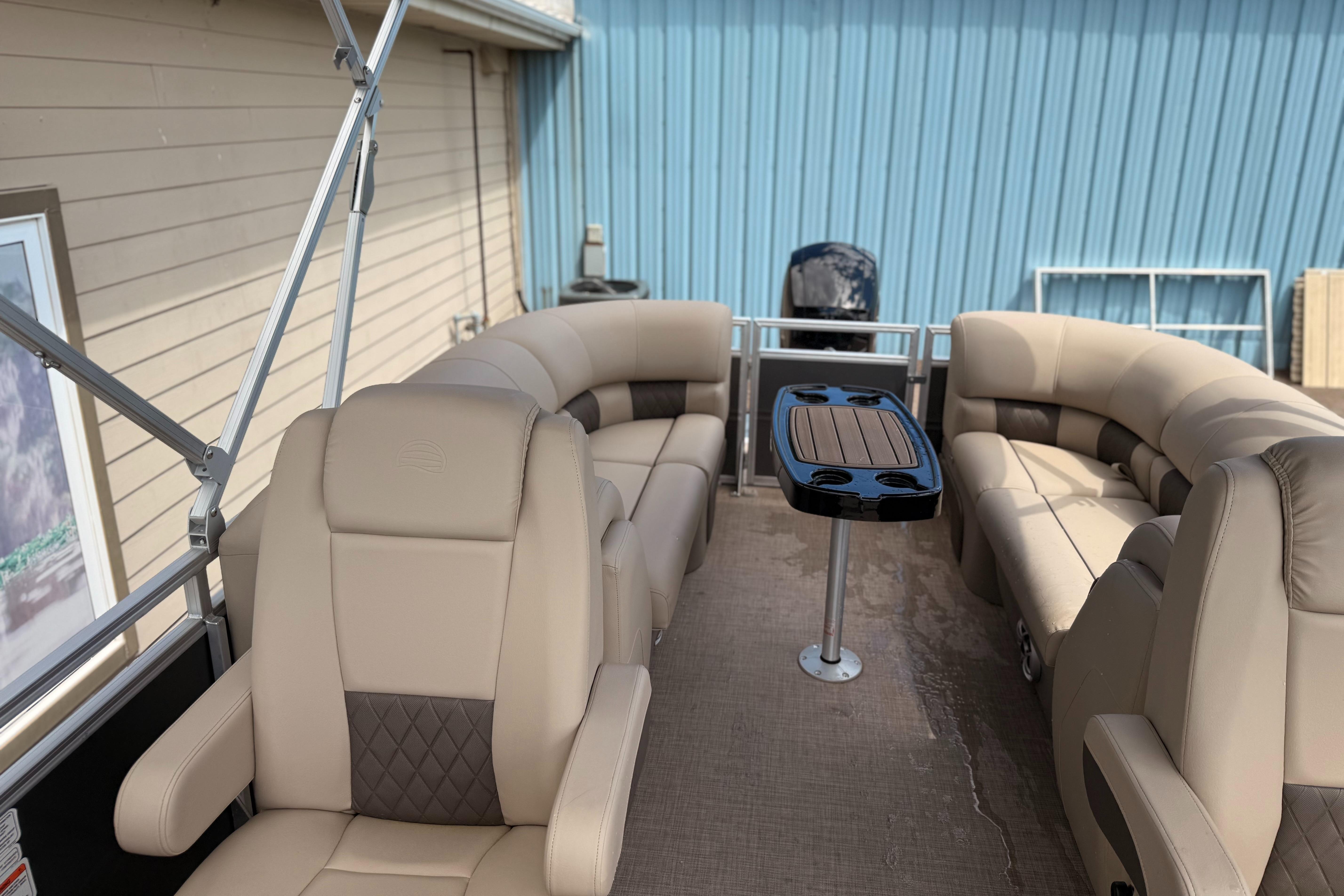 2024 Sun Tracker Party Barge 24 DLX interior with beige seating and central table.
