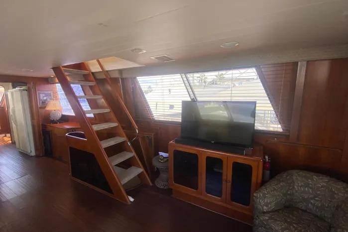 1990 Viking Motor Yacht interior with wooden stairs, TV, and cozy seating area.