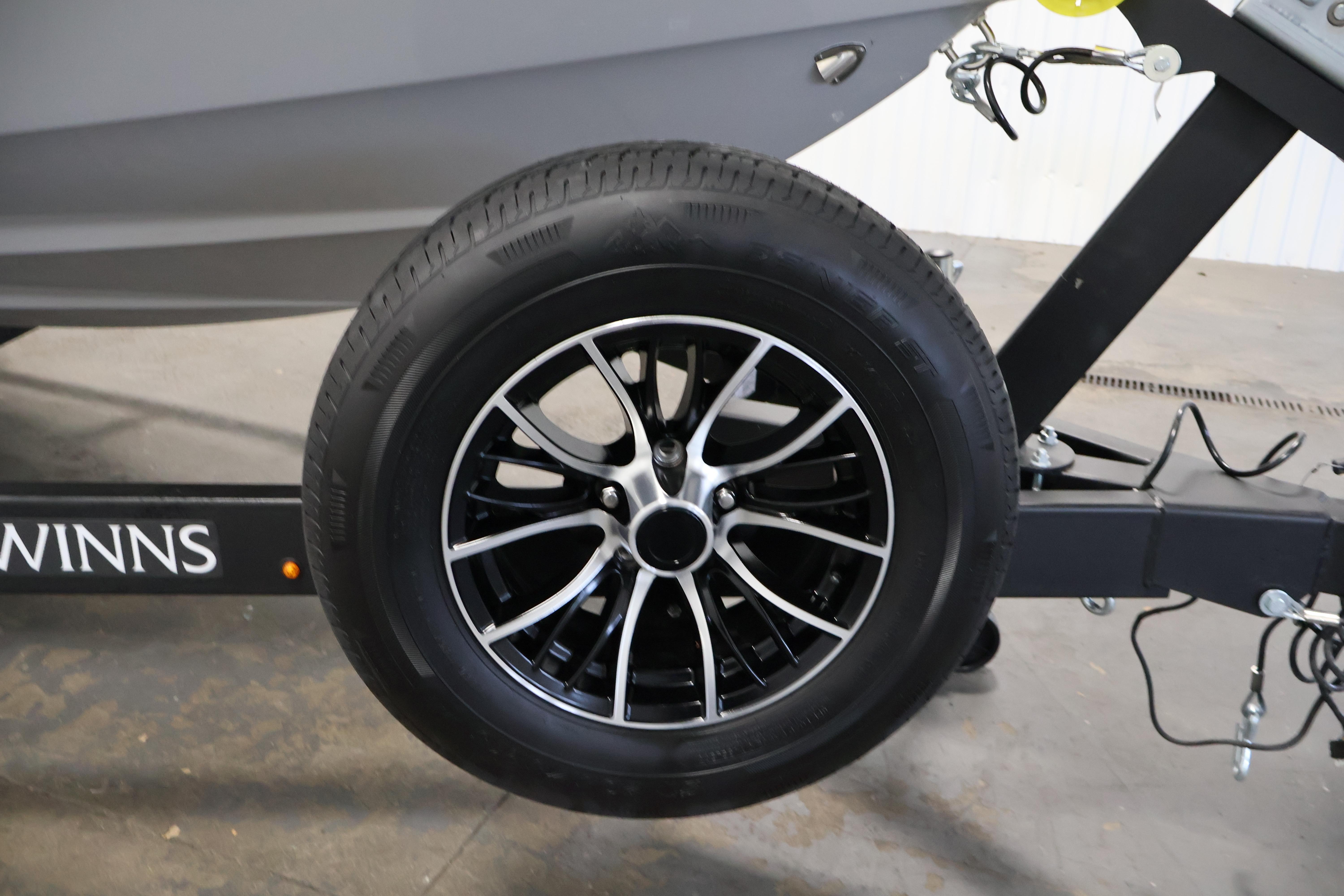 Trailer wheel of 2026 Four Winns H4 Freedom boat, featuring sleek black alloy rims.