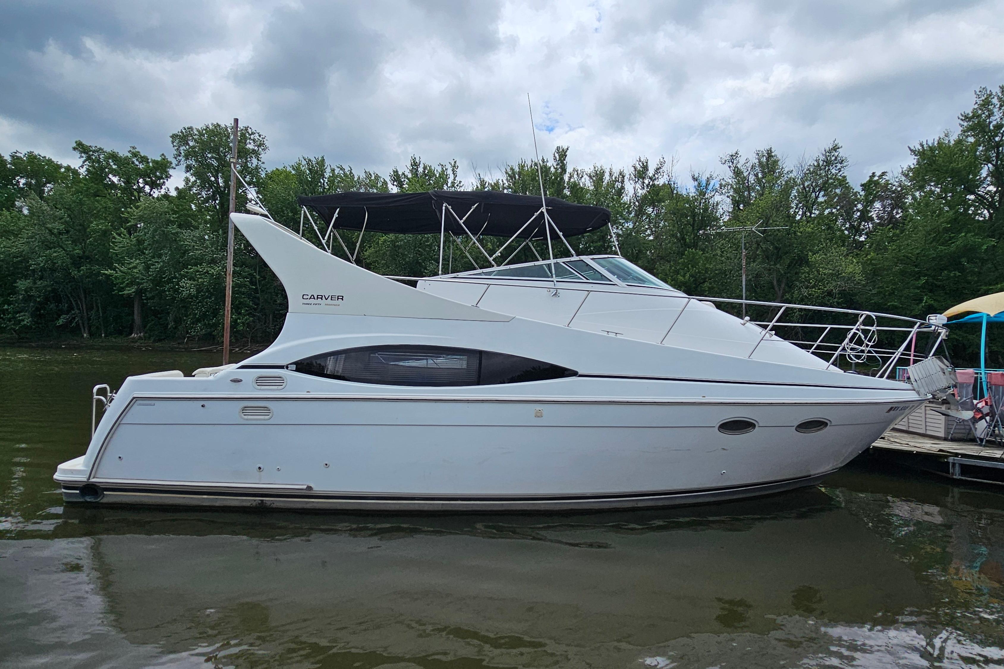 1999 Carver 350 Mariner yacht docked on a calm river, surrounded by lush greenery.