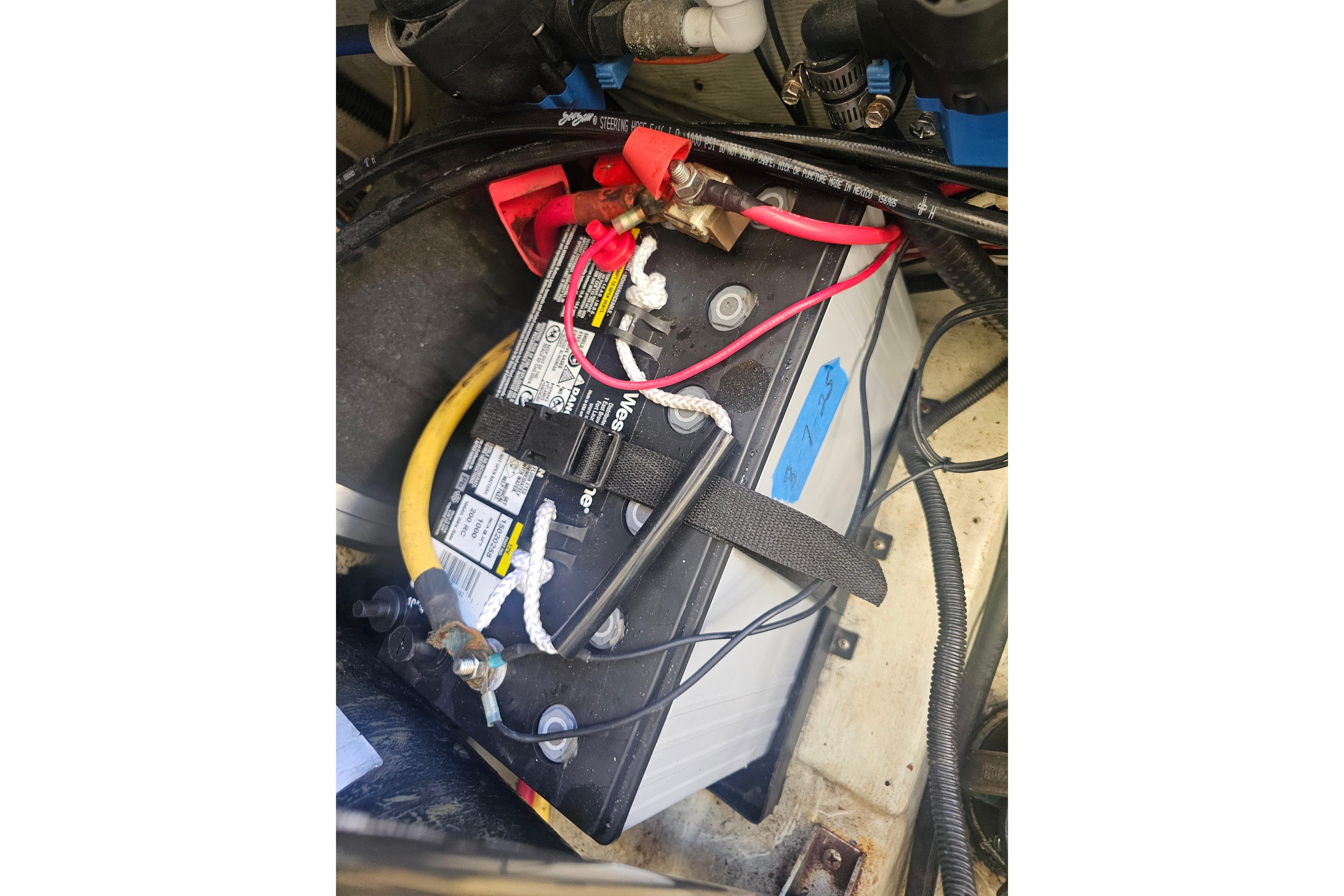Battery compartment of a 2001 Pursuit 3000 Express boat with connected cables.
