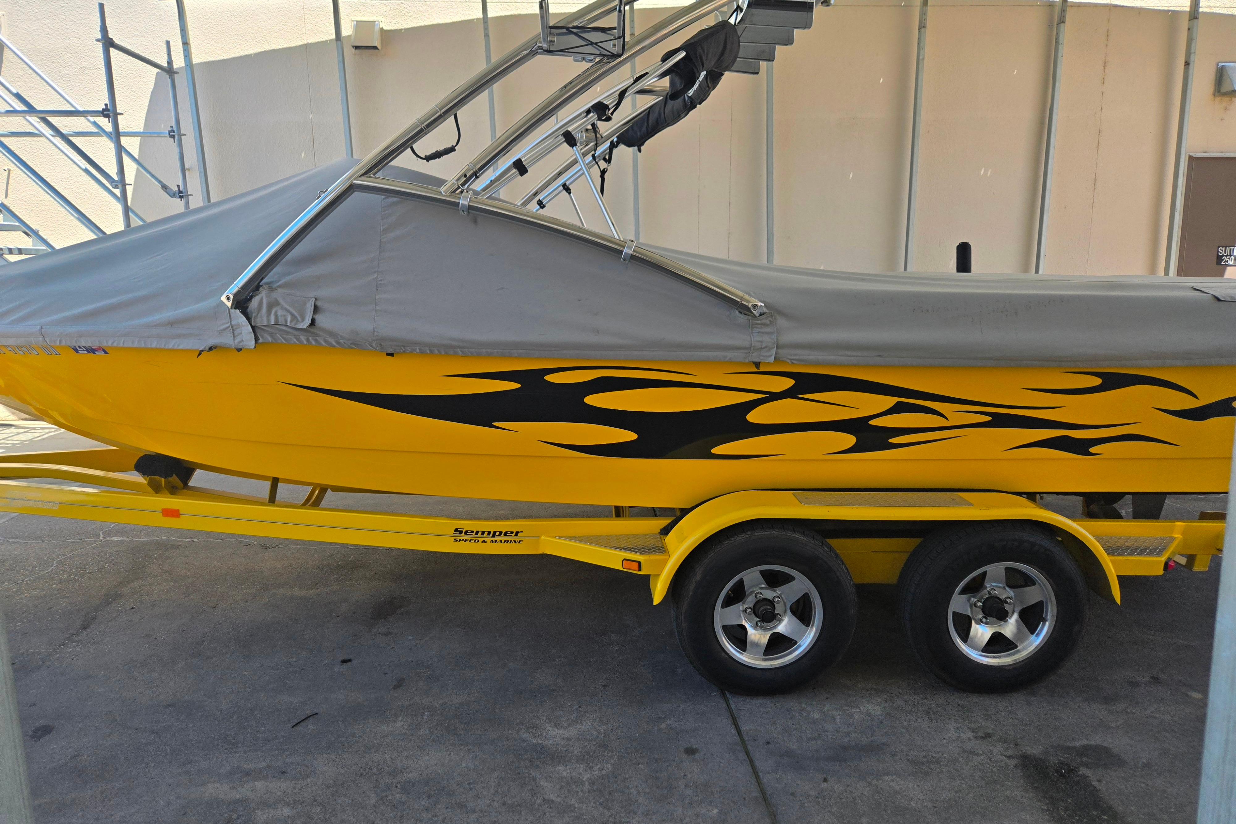 Yellow 2007 Calabria CAL AIR PRO V boat with flame decals on a trailer.