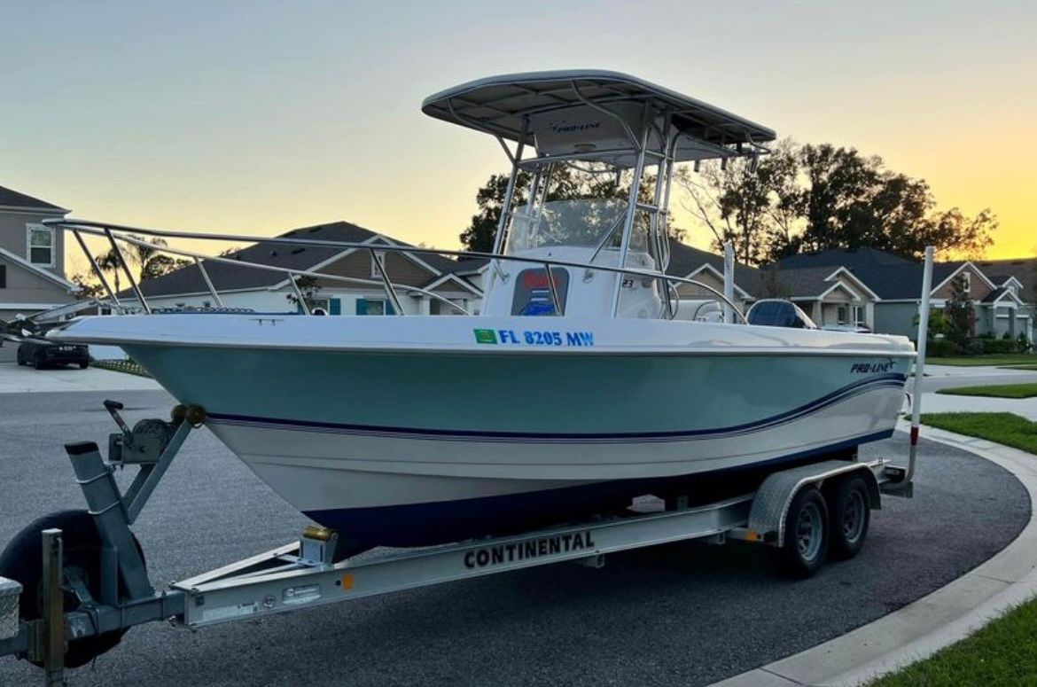 A 2005 Pro-Line 23 Sport boat on a trailer in a residential area.