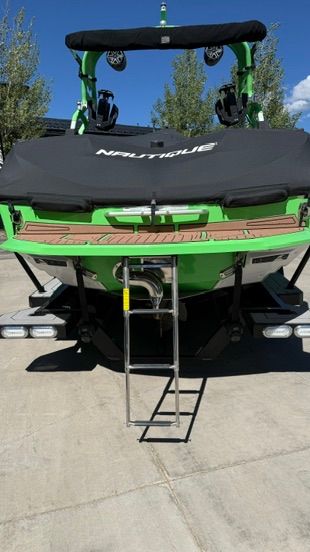 A green boat with a black cover and a ladder at the stern.