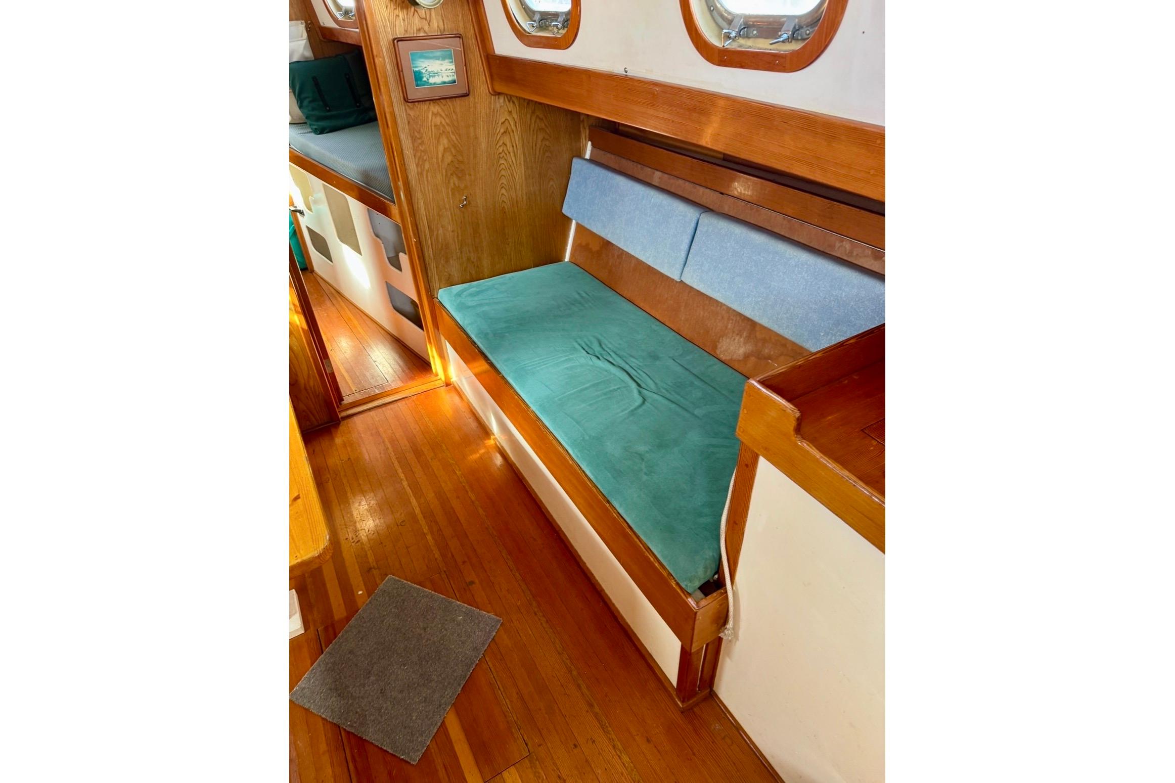 Interior of 1987 Custom Steel Cutter with wooden flooring and cushioned seating.