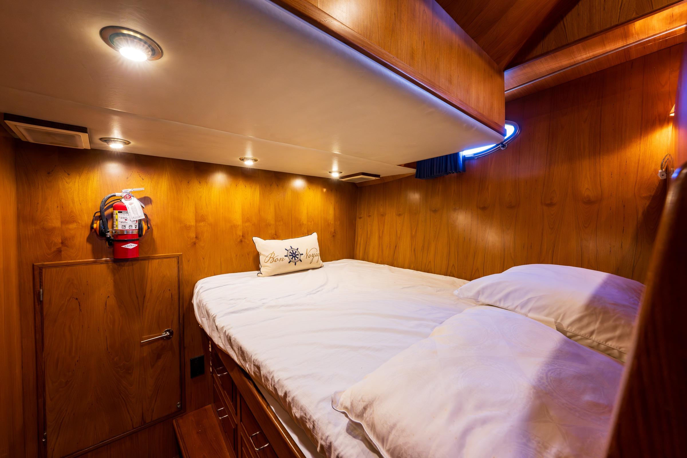 Cozy cabin interior of 1990 Ocean Alexander 48 Sedan yacht with wooden paneling and soft lighting.