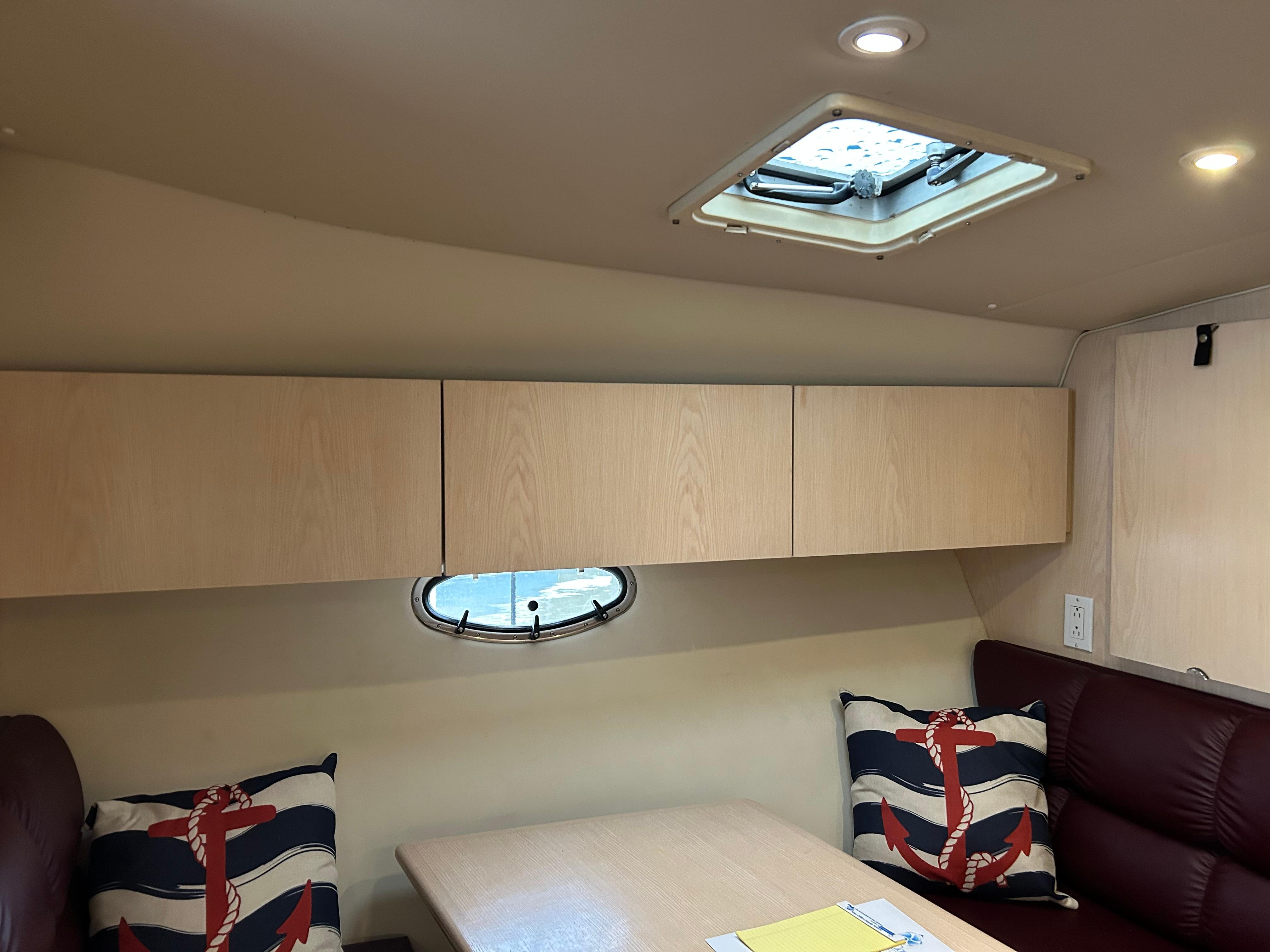 1997 Tiara Yachts 3500 Express cabin interior with nautical-themed cushions and overhead storage.