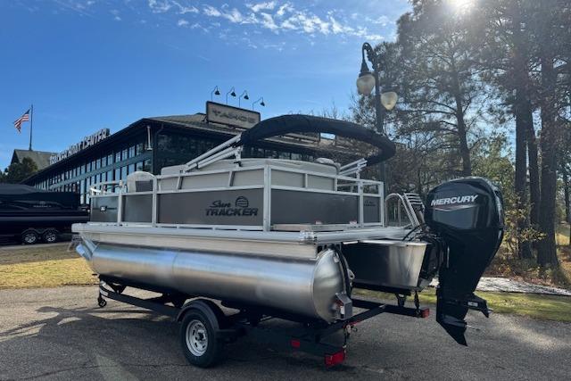2026 Sun Tracker Bass Buggy 16 XL Select pontoon boat with Mercury engine, parked outdoors.
