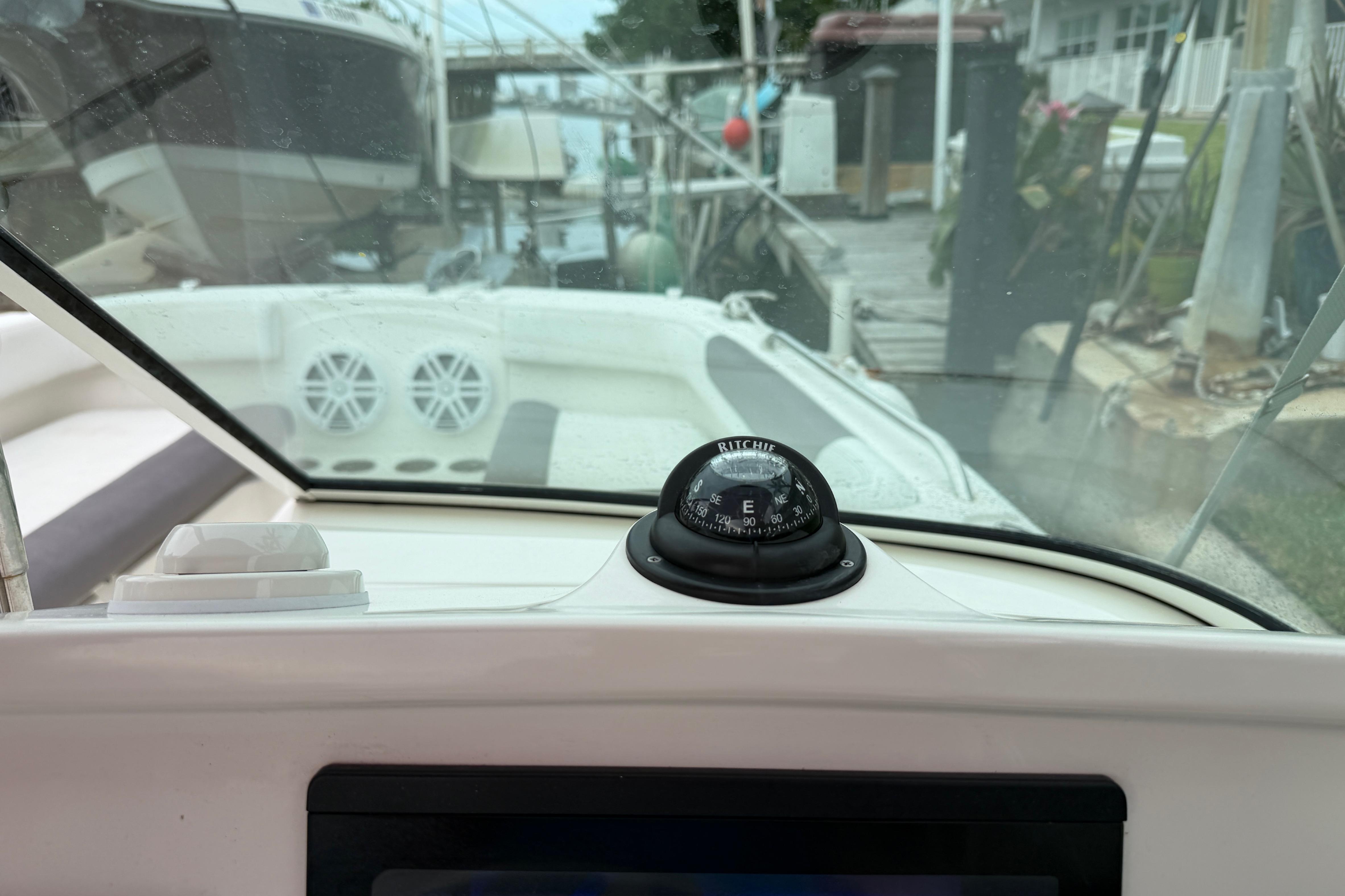 Interior view of a 2019 World Cat 230 DC boat with compass and docked surroundings.