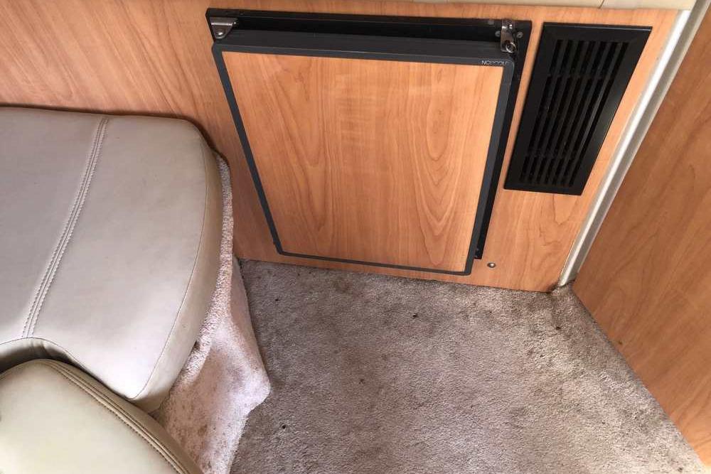 Interior of a 1999 Regal Commodore 2760 boat with seating and wooden paneling.