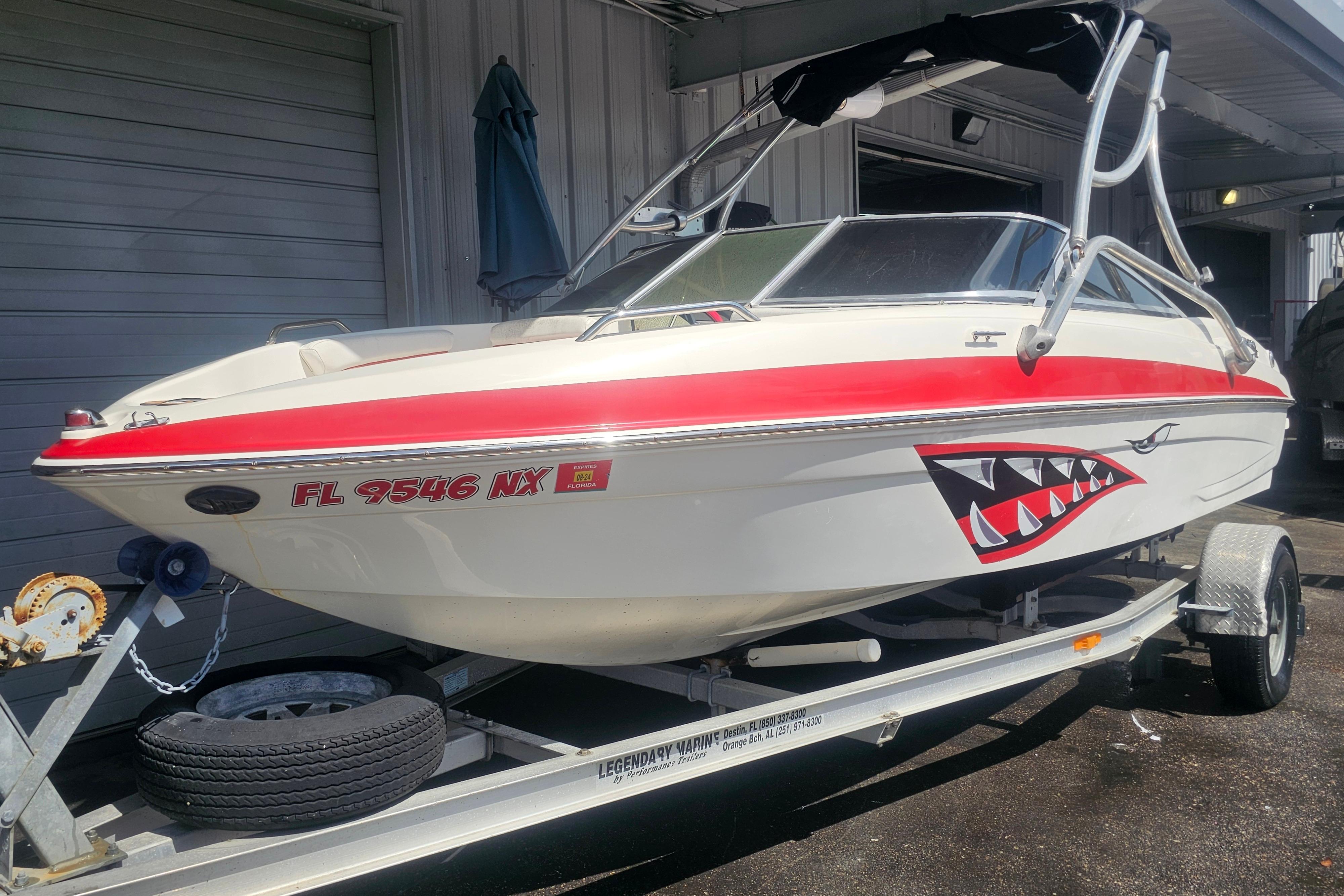 2008 Glastron GT 205 boat with shark mouth decal on trailer, parked outdoors.