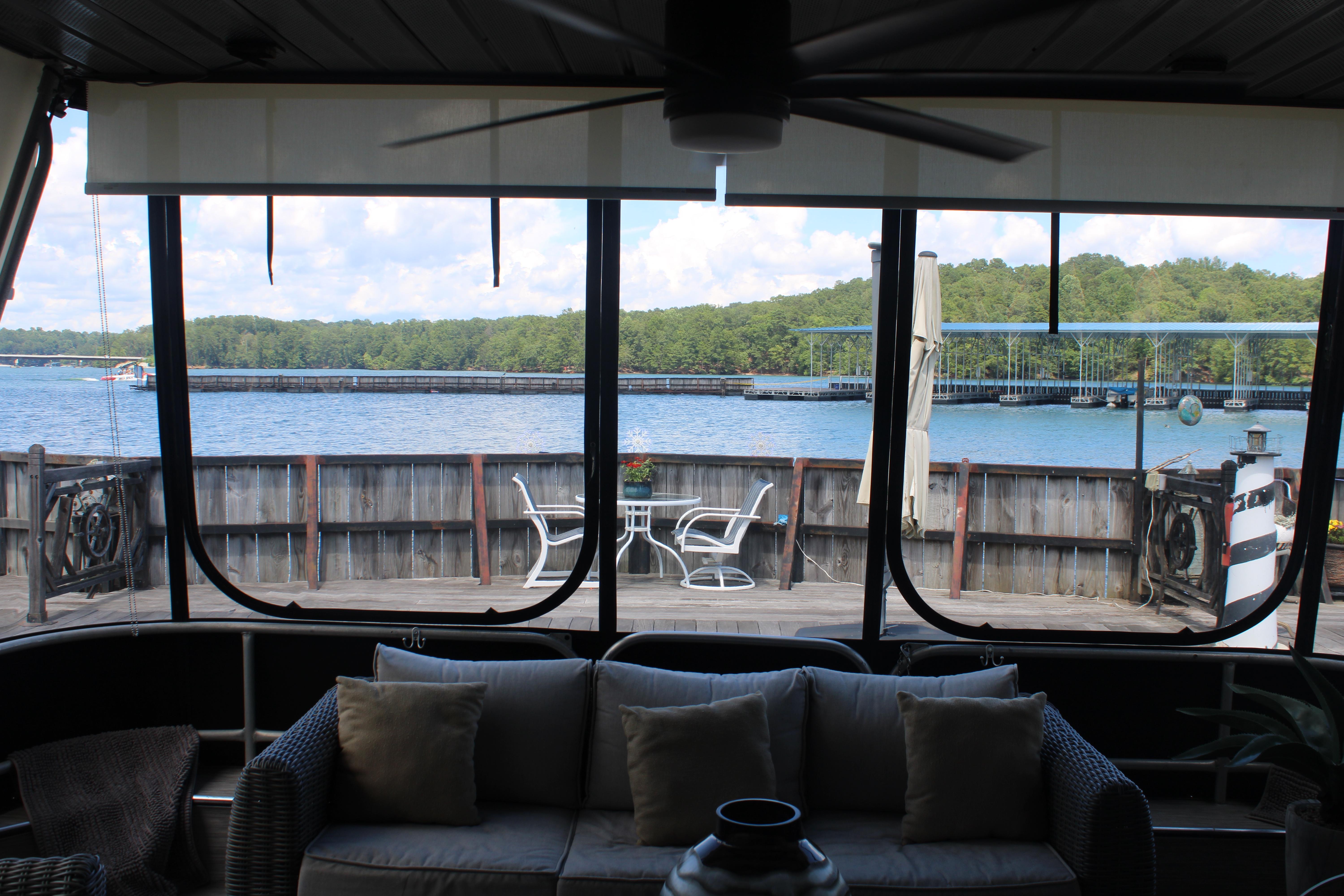 Interior view from a 1992 Sumerset 66 houseboat, overlooking a serene lake and dock.