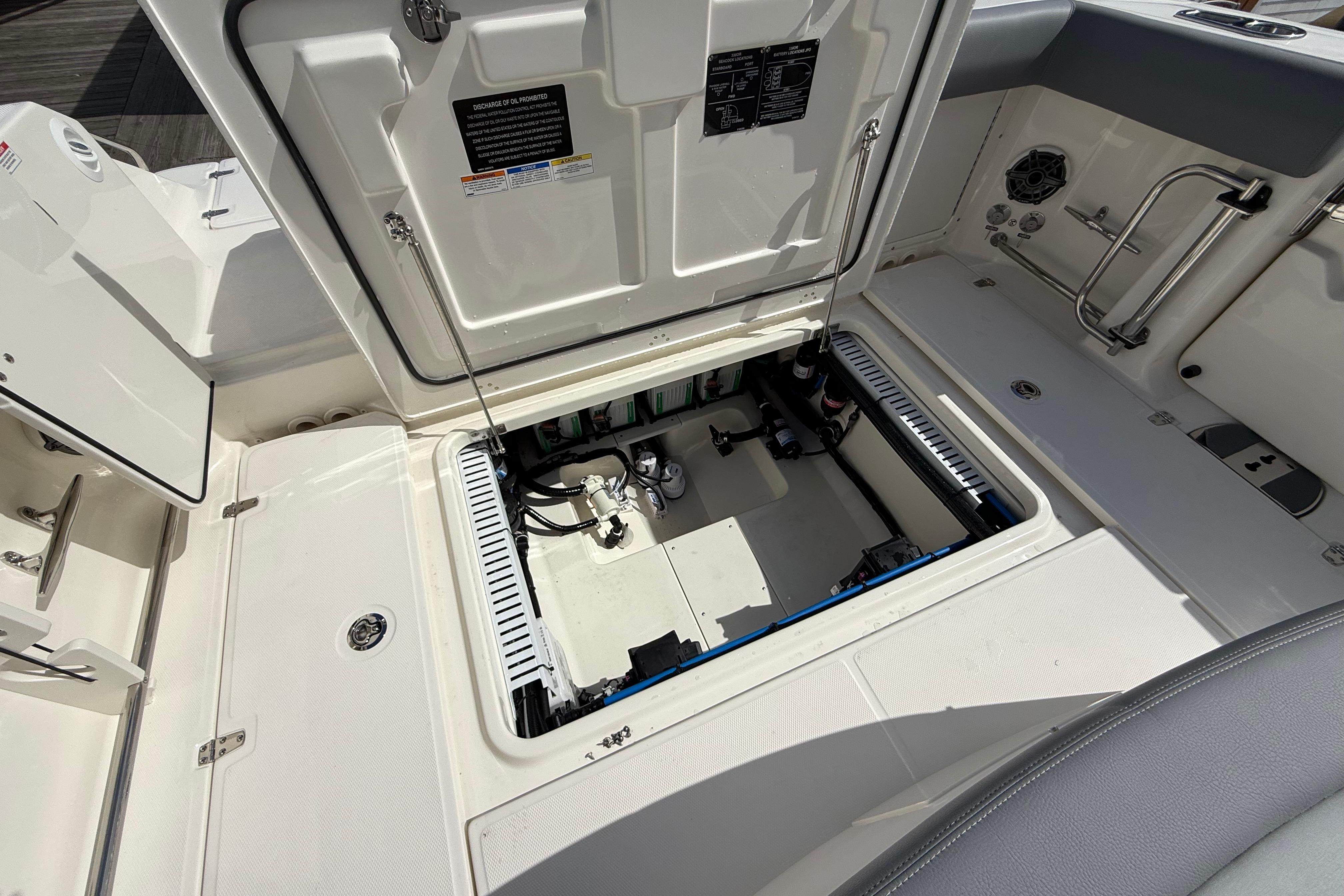 Open hatch of 2026 Boston Whaler 330 Outrage boat, revealing internal components and storage.
