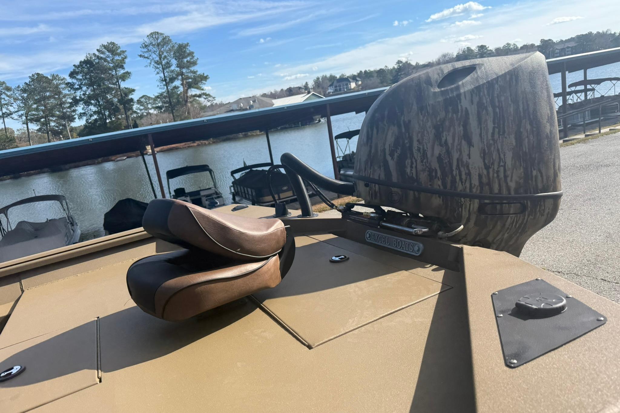 2026 Excel 206 Stalker CC boat with camo motor cover, docked by a serene lake.