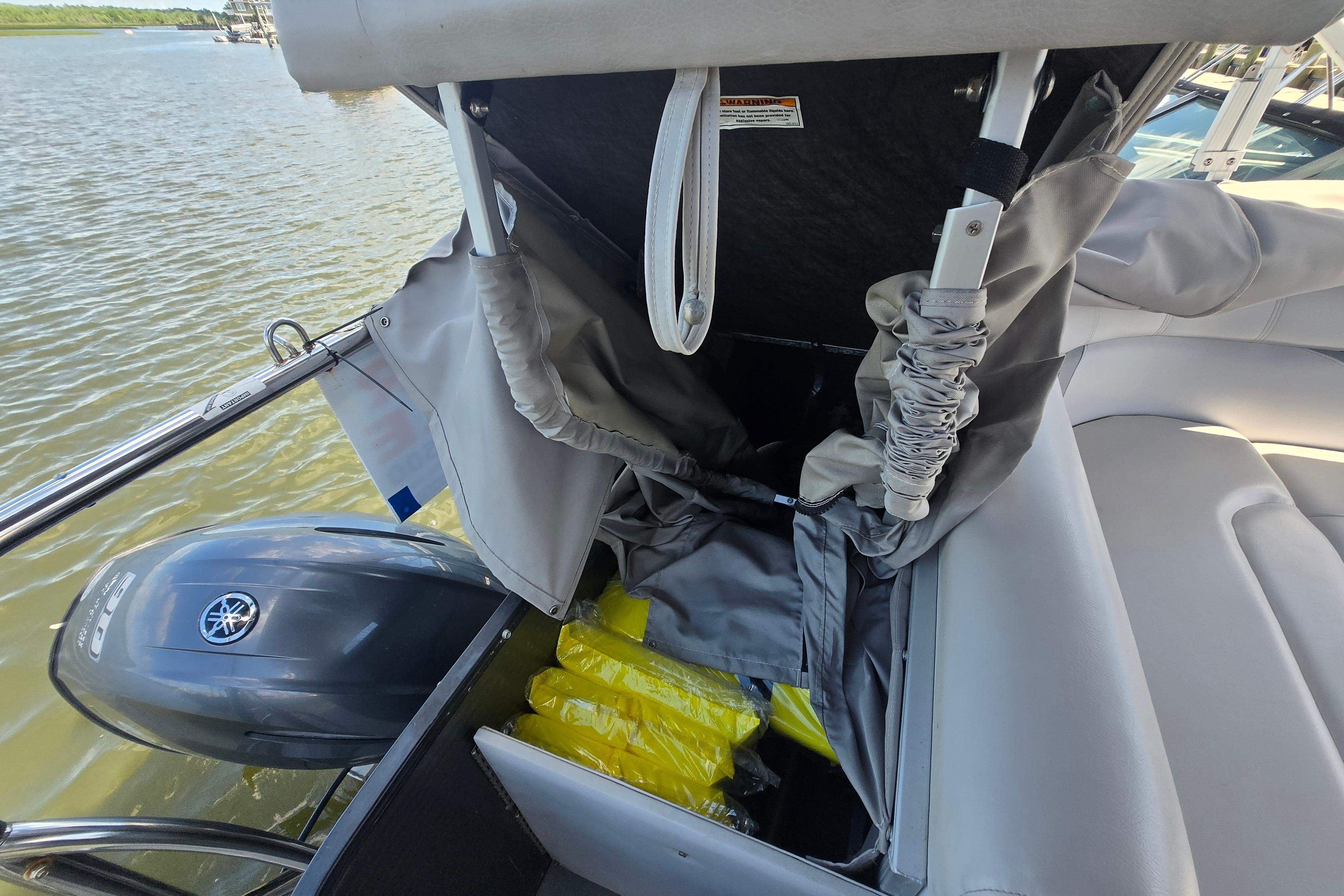 2017 Godfrey Sweetwater 2286 SB boat with Yamaha motor and storage compartment open.