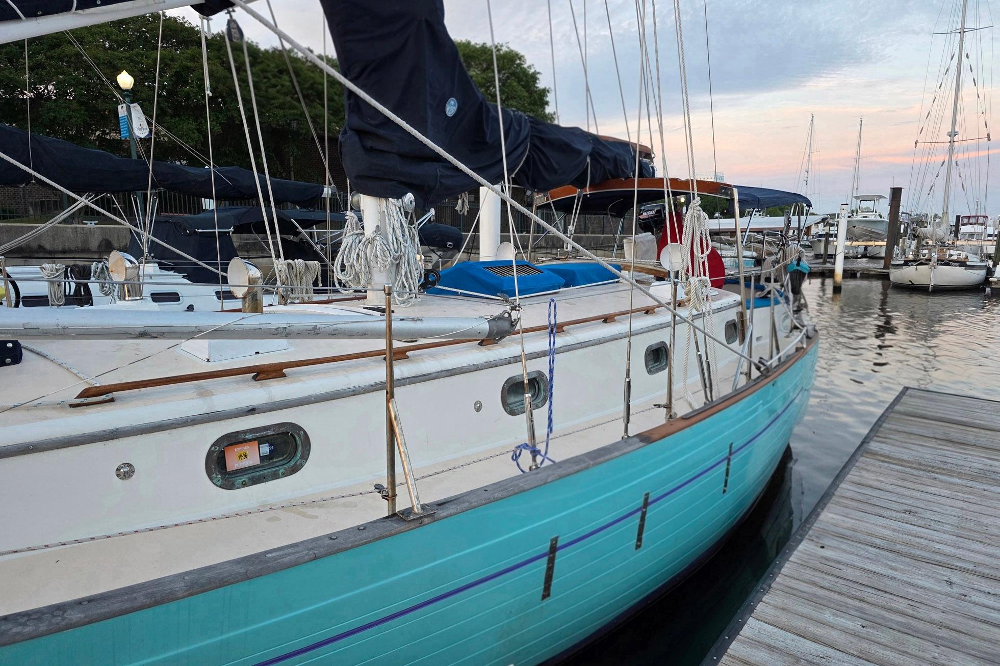 1982 Tayana 37 sailboat docked at marina, featuring turquoise hull and rigging.