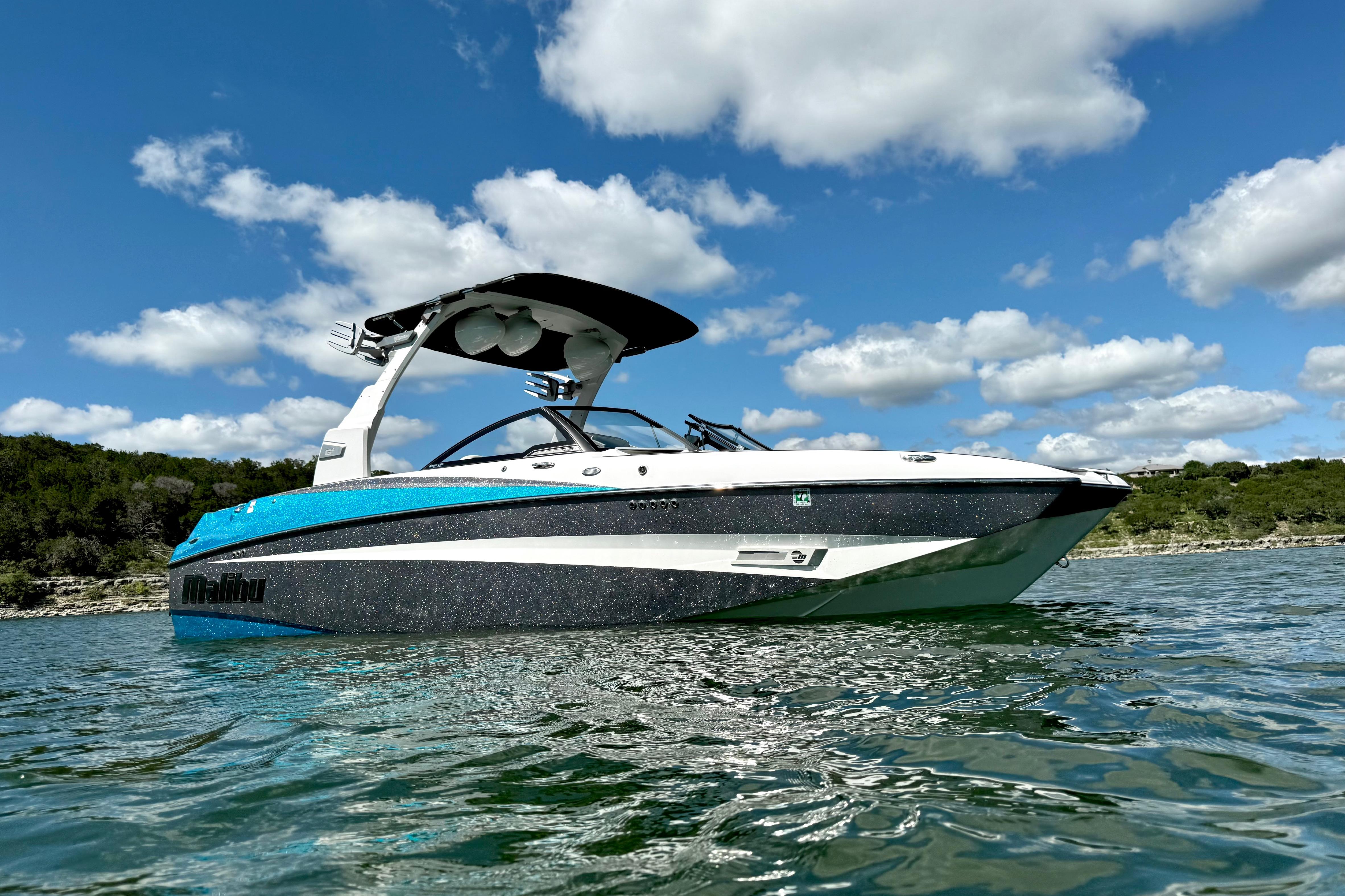 2017 Malibu M235 boat on a lake under a clear blue sky.