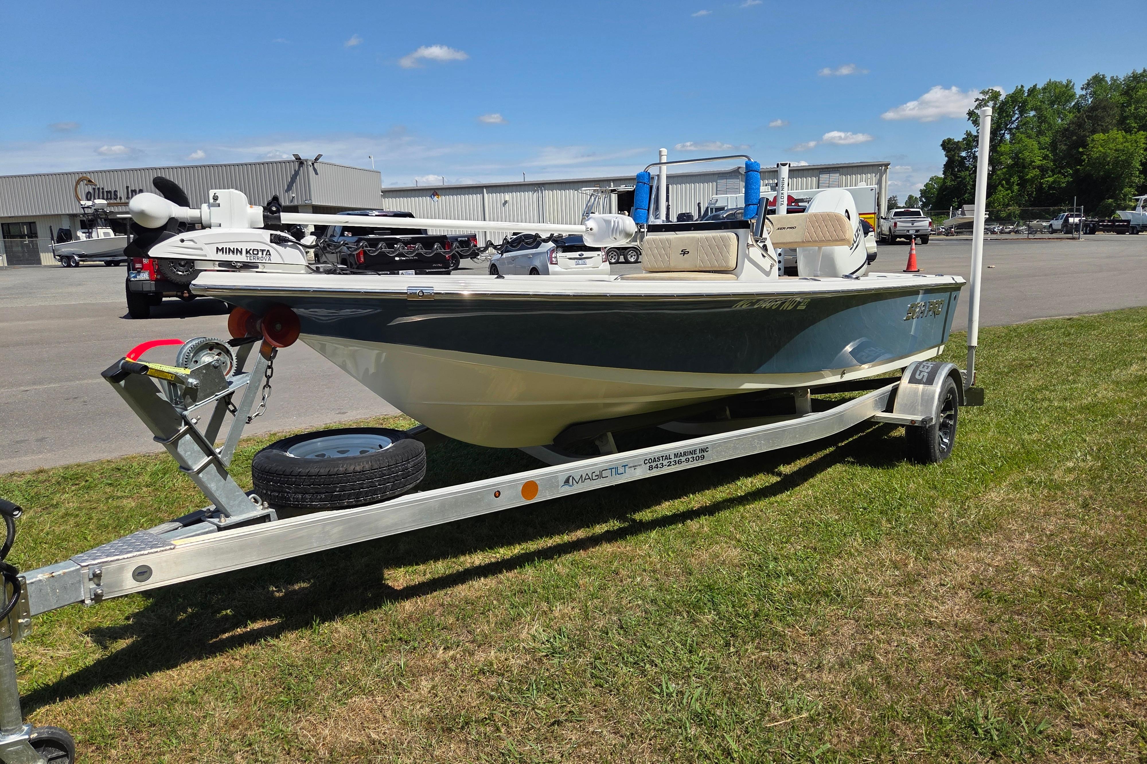 2024 Sea Pro 172 Bay boat on trailer, parked on grass under clear blue sky.