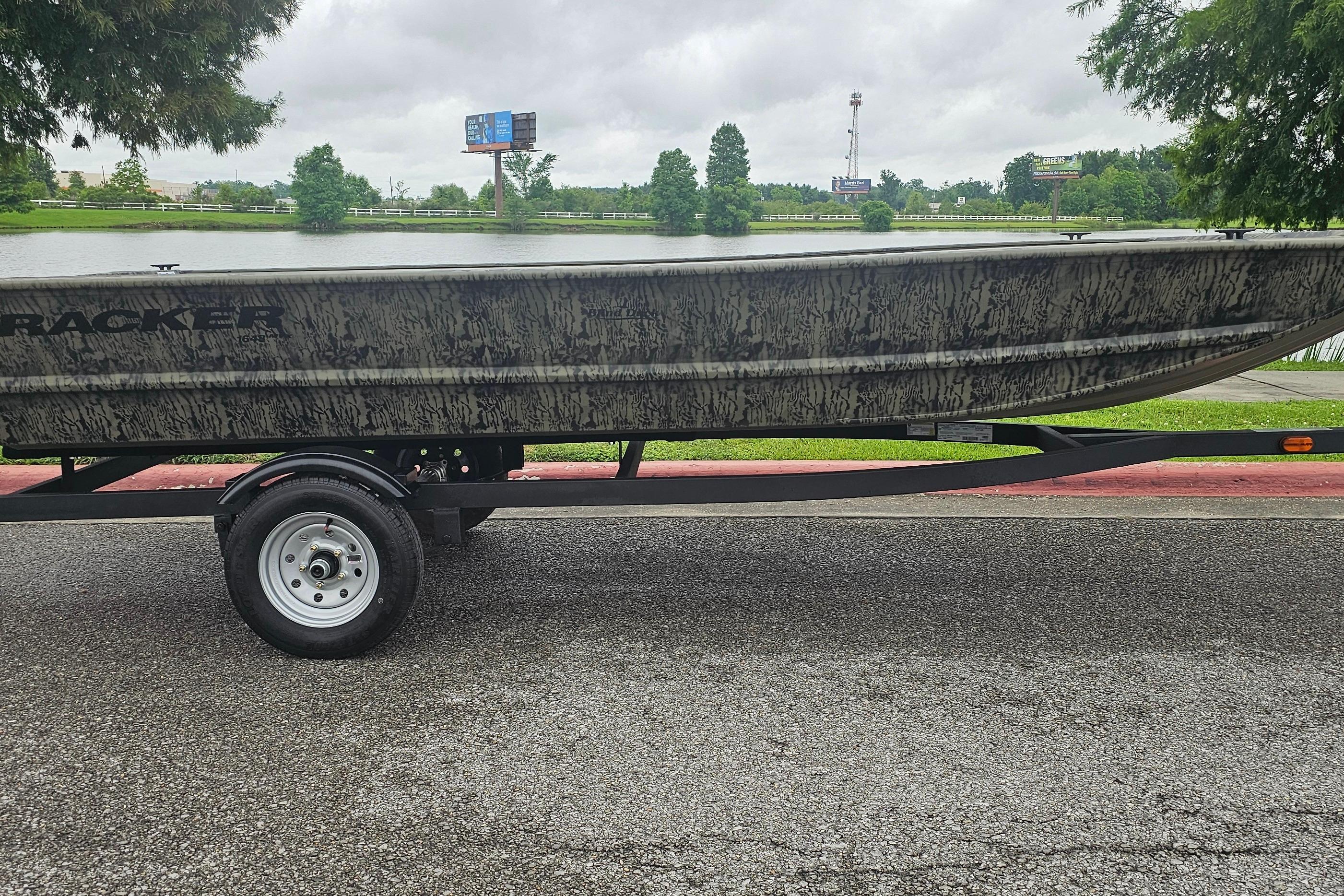 2026 Tracker Grizzly 1648 Utility boat on trailer by a lake.