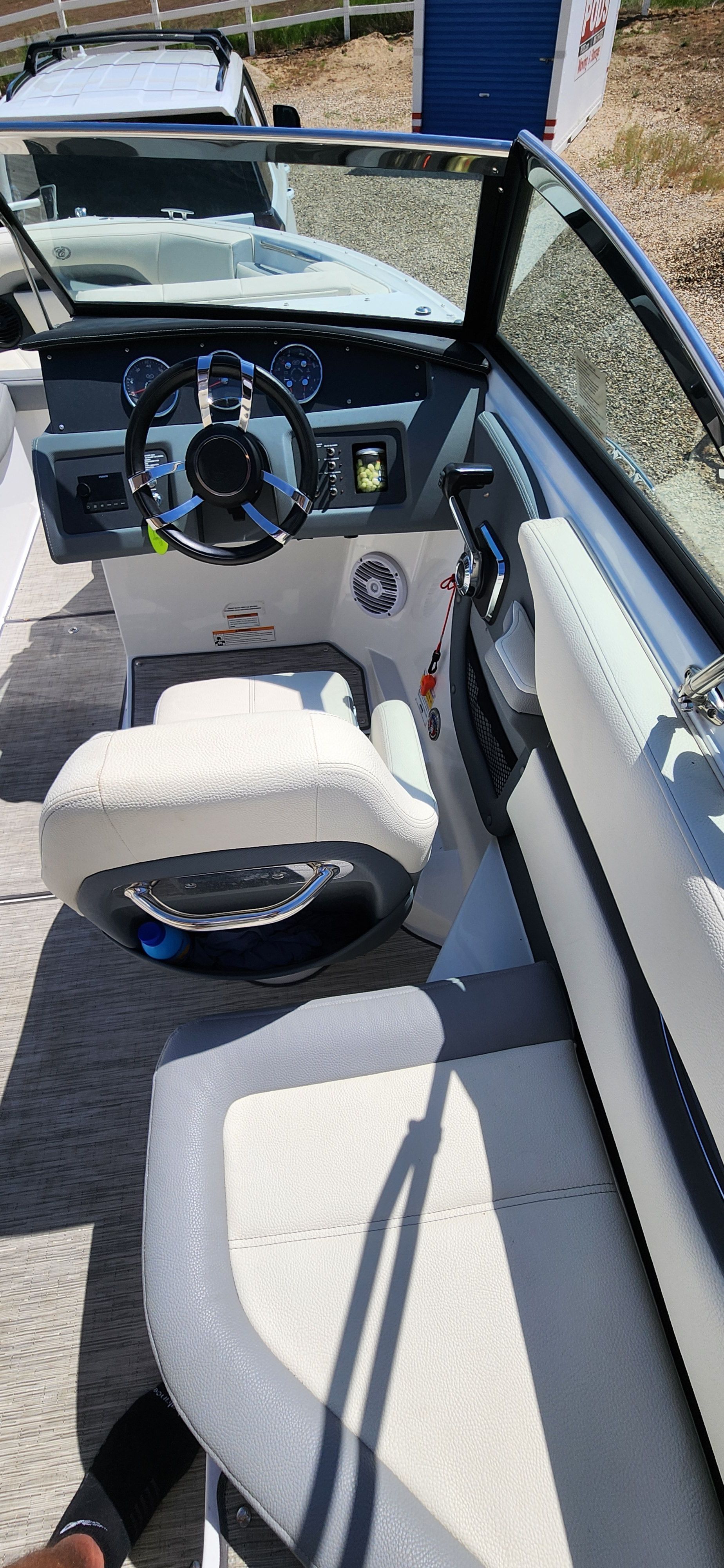 Interior view of a modern boat with white seating and steering wheel.