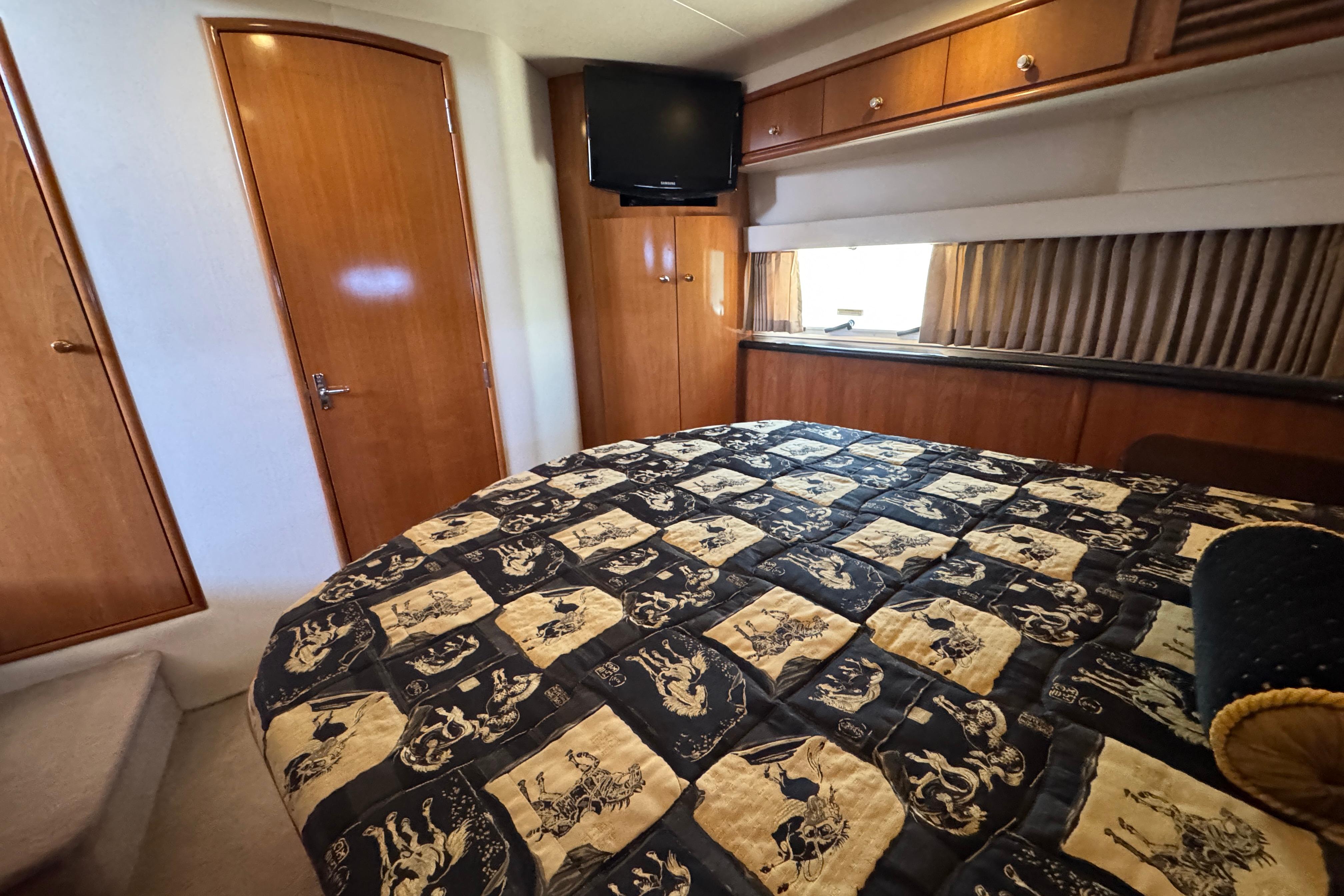 Luxurious bedroom interior of 2002 Carver 396 Motor Yacht with patterned bedding and wood accents.