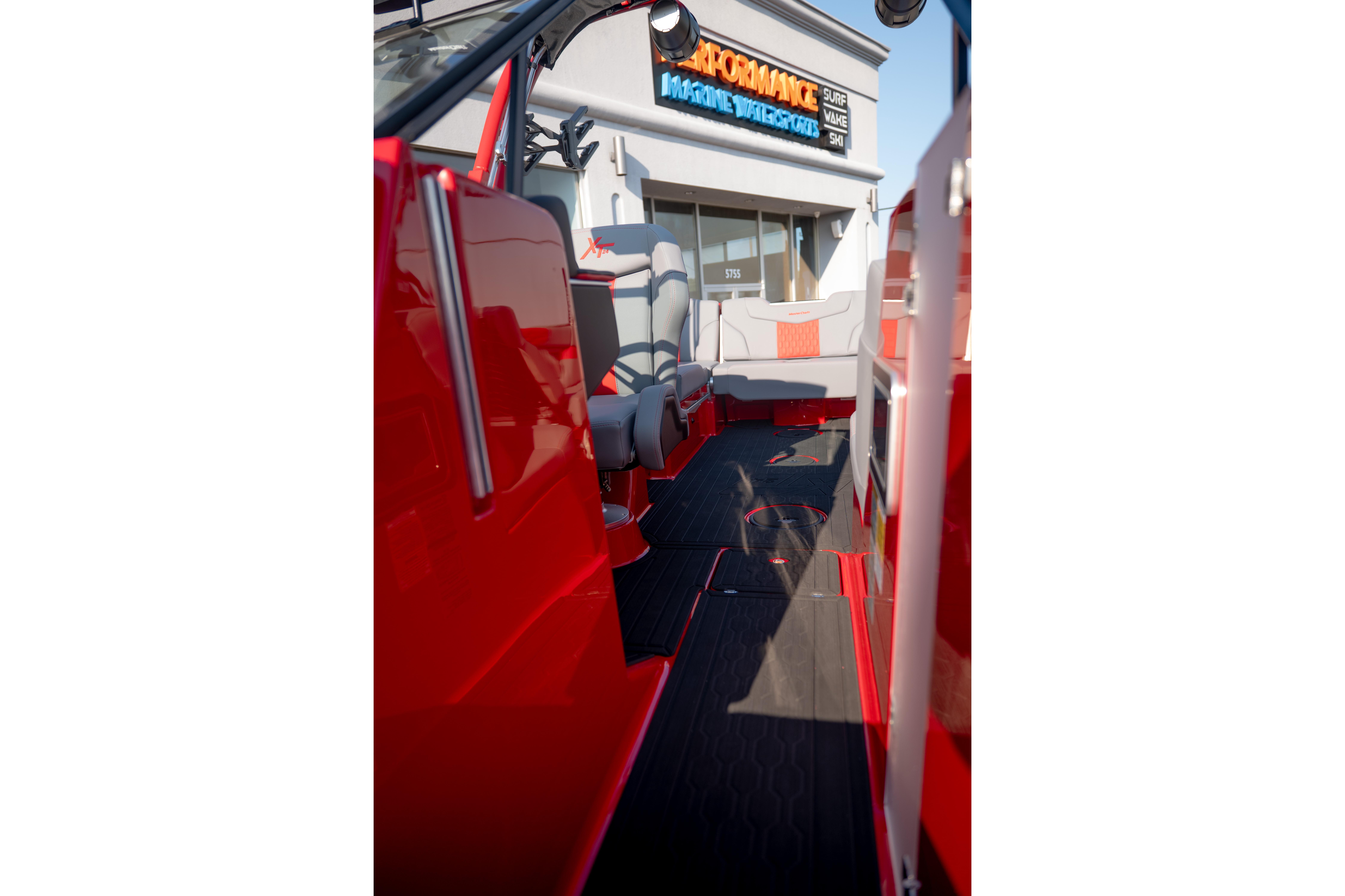 2027 MasterCraft XT24 boat interior with red and gray seating, outside a marine store.