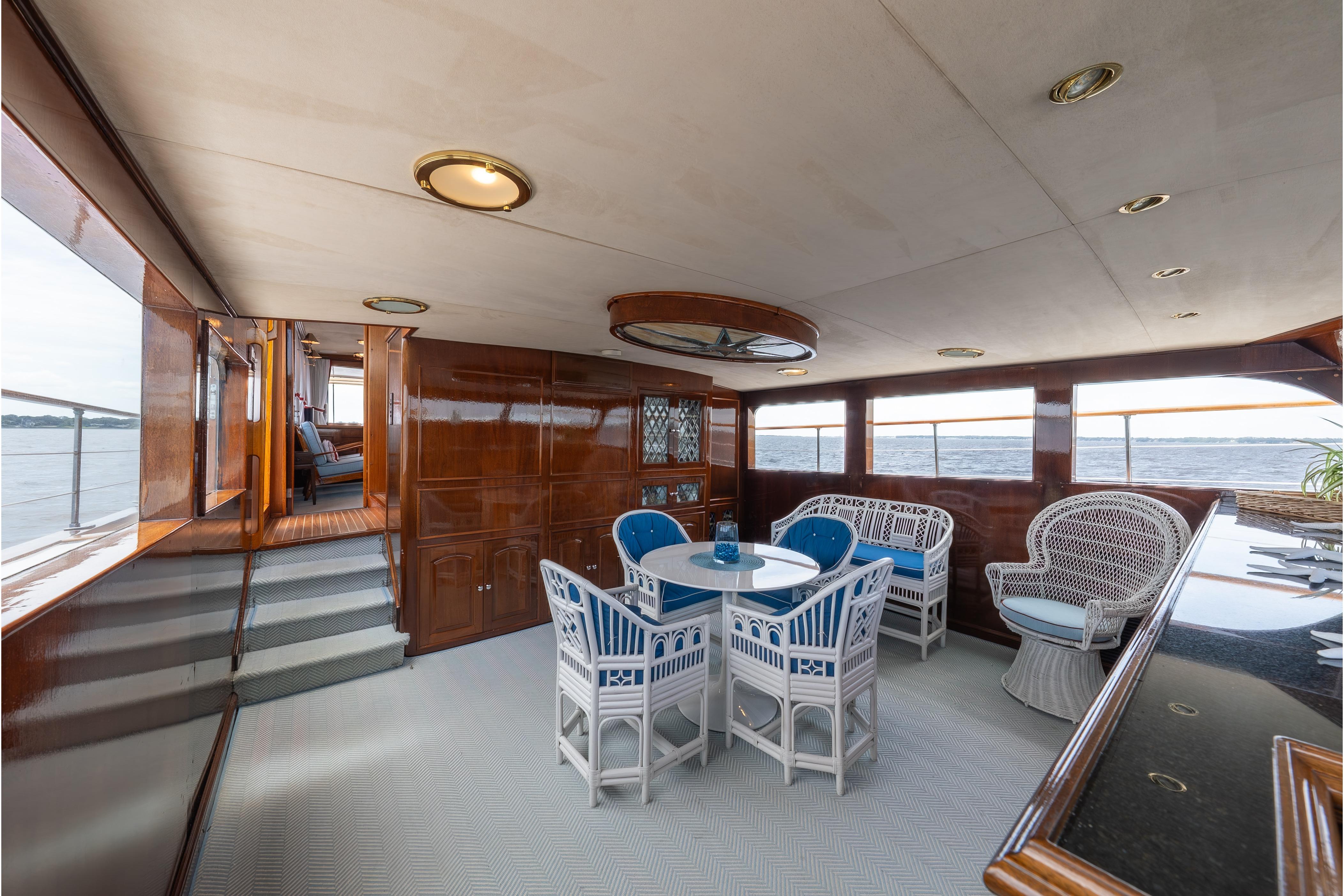 Luxurious 1963 Trumpy Classic yacht interior with elegant wicker furniture and ocean view.