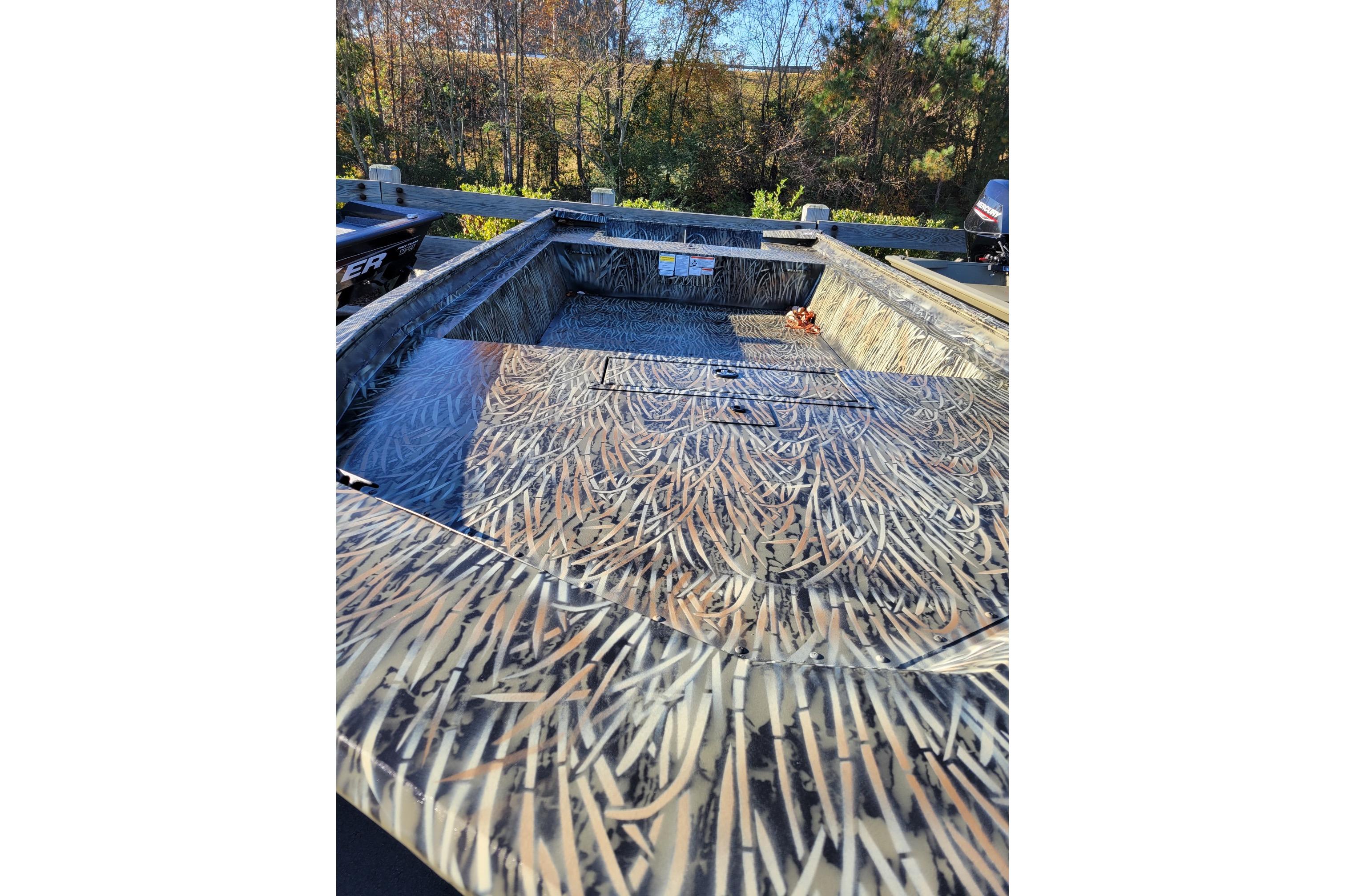 2025 Tracker Grizzly 1860 Utility boat with camouflage pattern, parked outdoors.