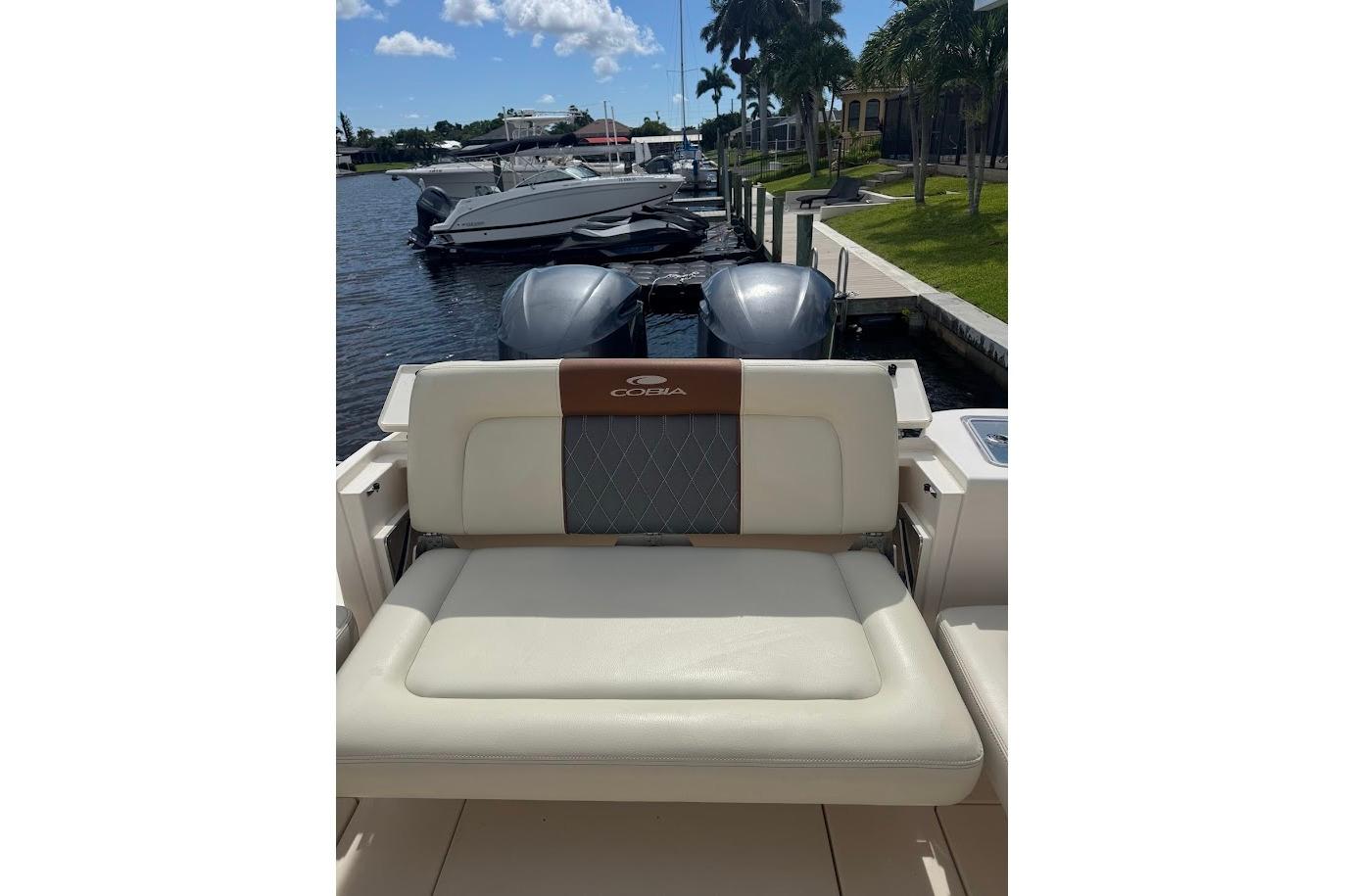 2020 Cobia 280 Dual Console boat with cushioned seating, docked by a waterfront.