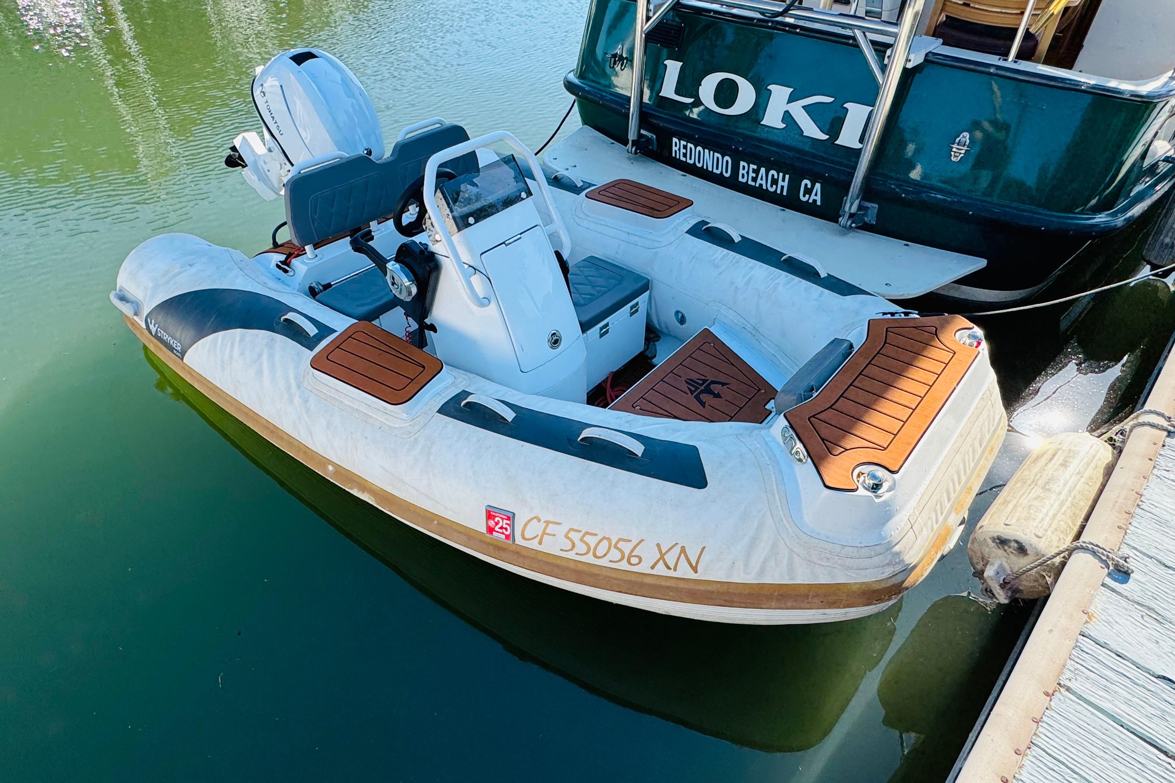 Inflatable boat docked beside a Nordic Tug 32, 1996 model, in a marina setting.