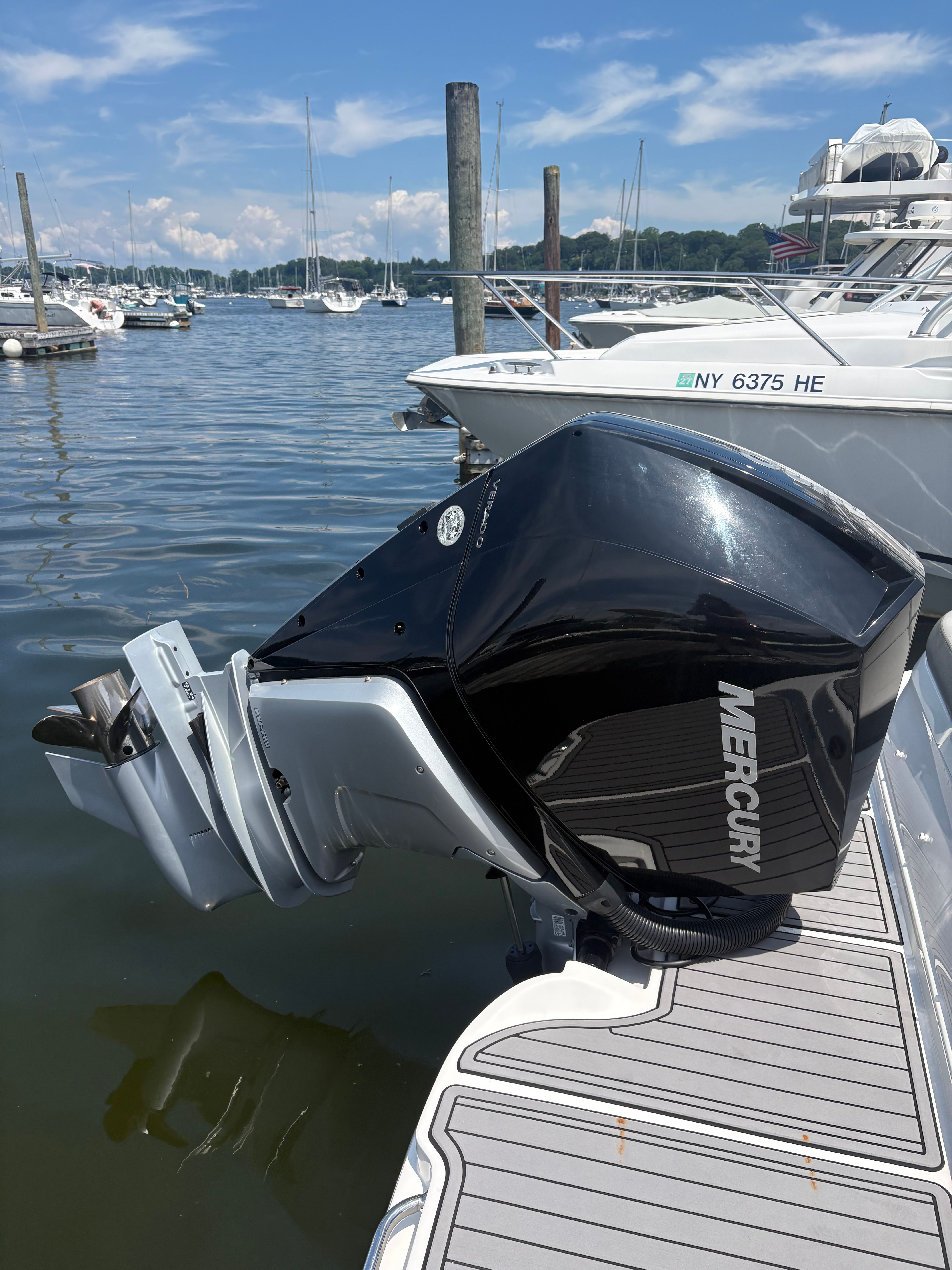 A Mercury outboard motor at a boat dock, surrounded by water and other boats.