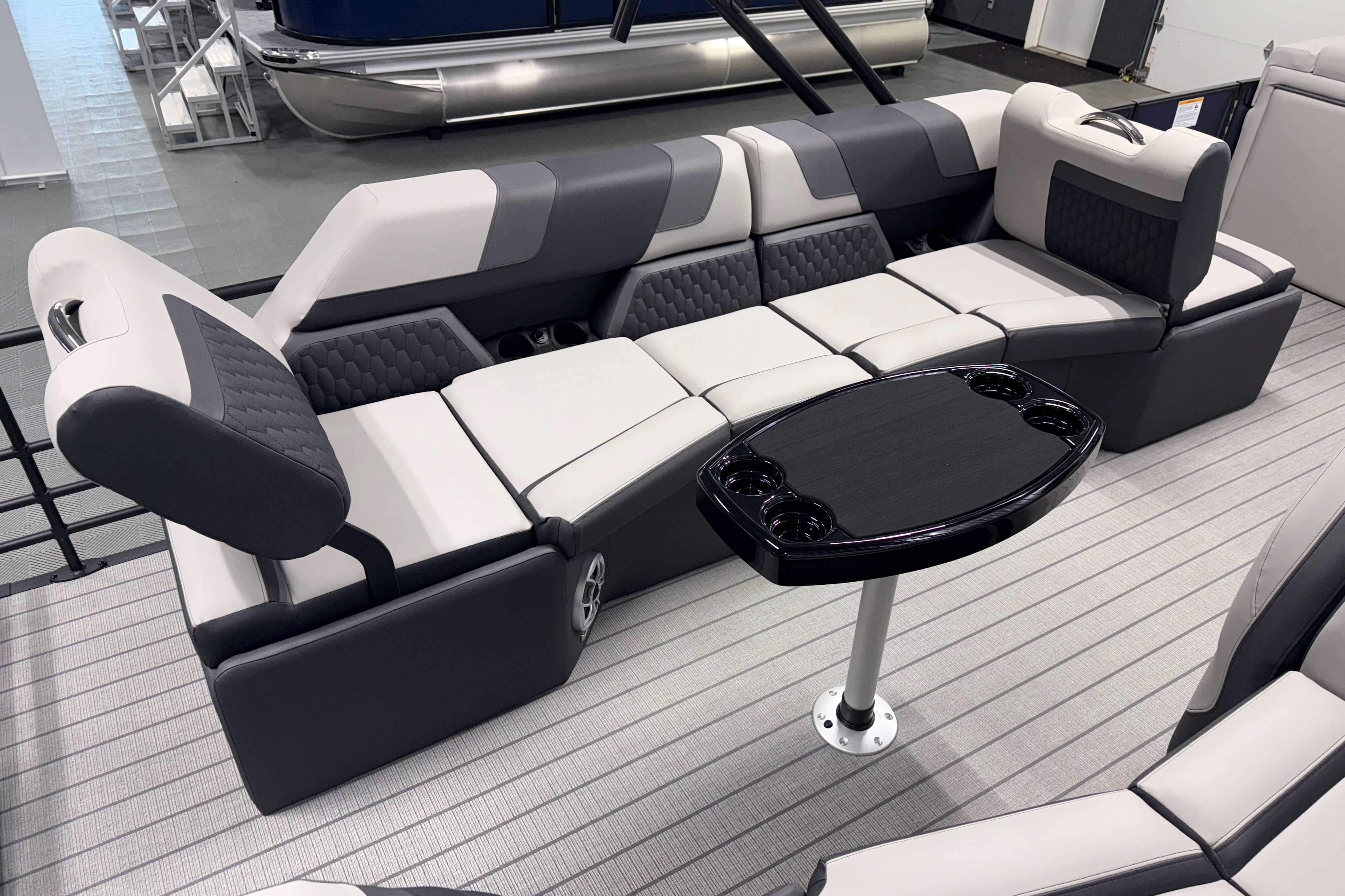 Luxurious seating on 2026 Sylvan L3 SLZ pontoon boat with sleek table and cup holders.