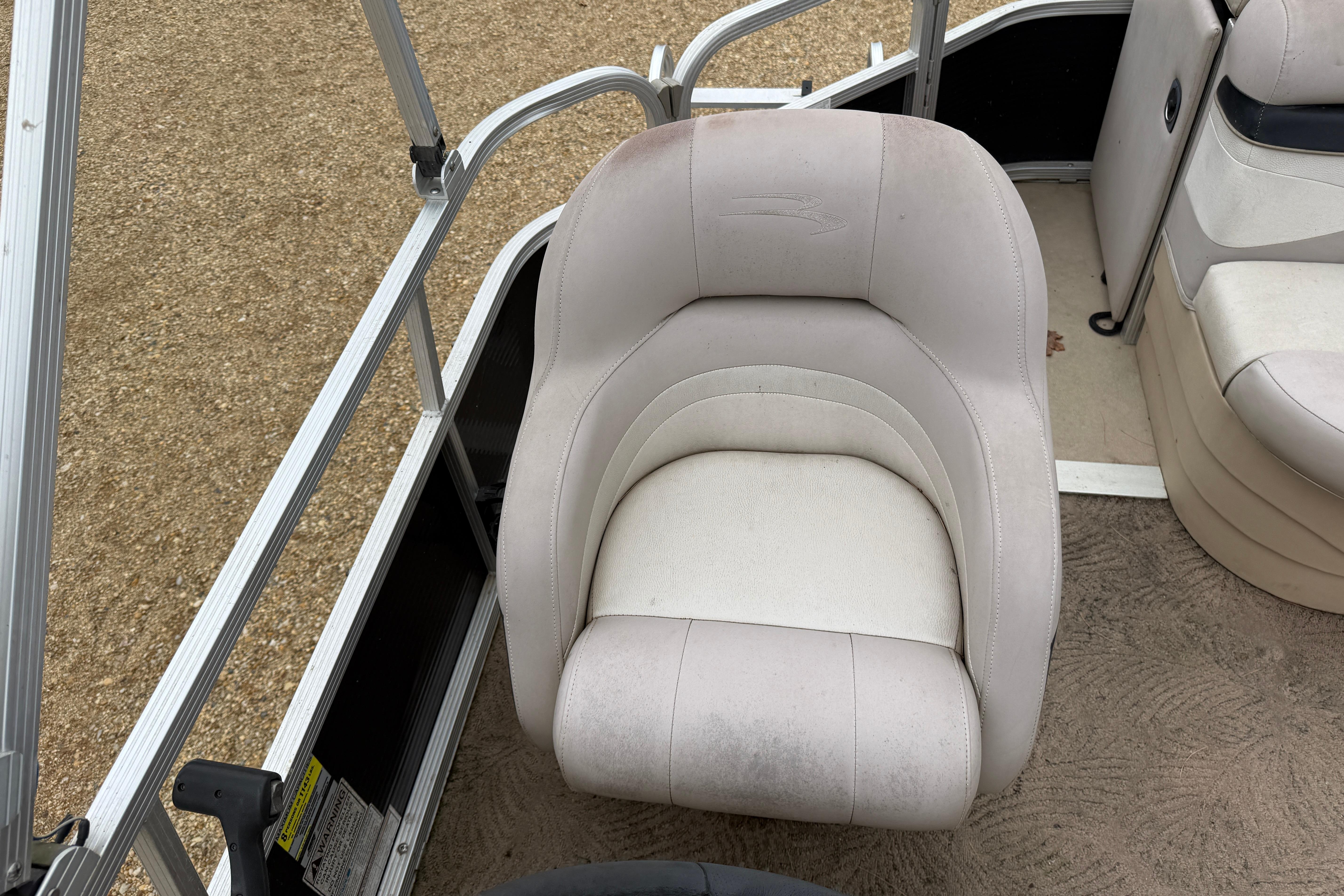 2010 Bennington 20SLi boat seat with beige upholstery and metal railing.