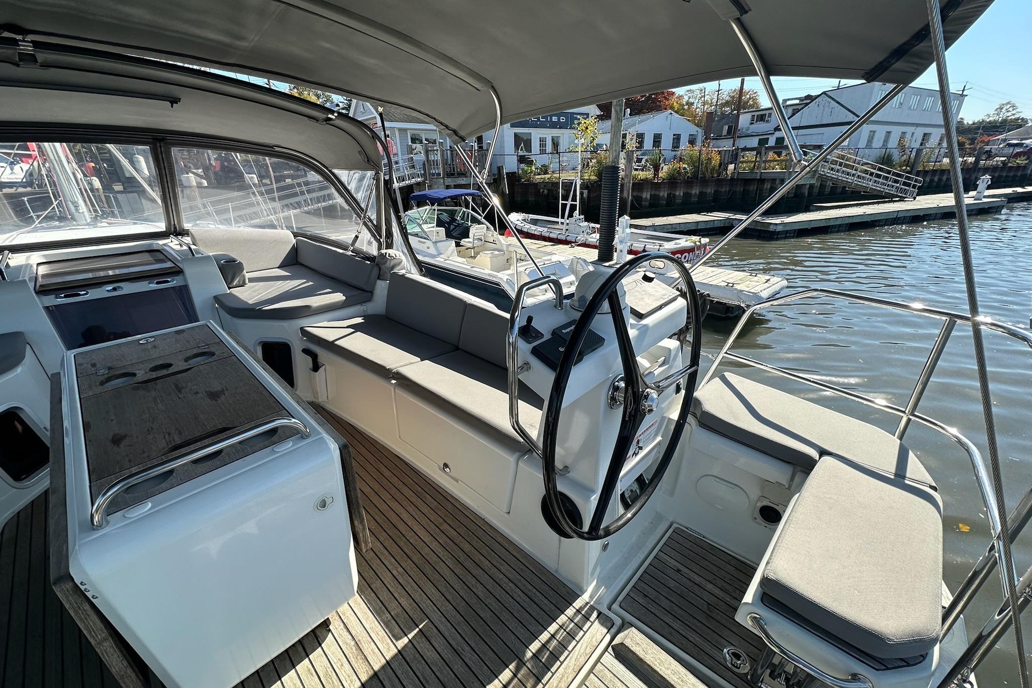 2018 Jeanneau 51 yacht cockpit with steering wheel, seating, and waterfront view.