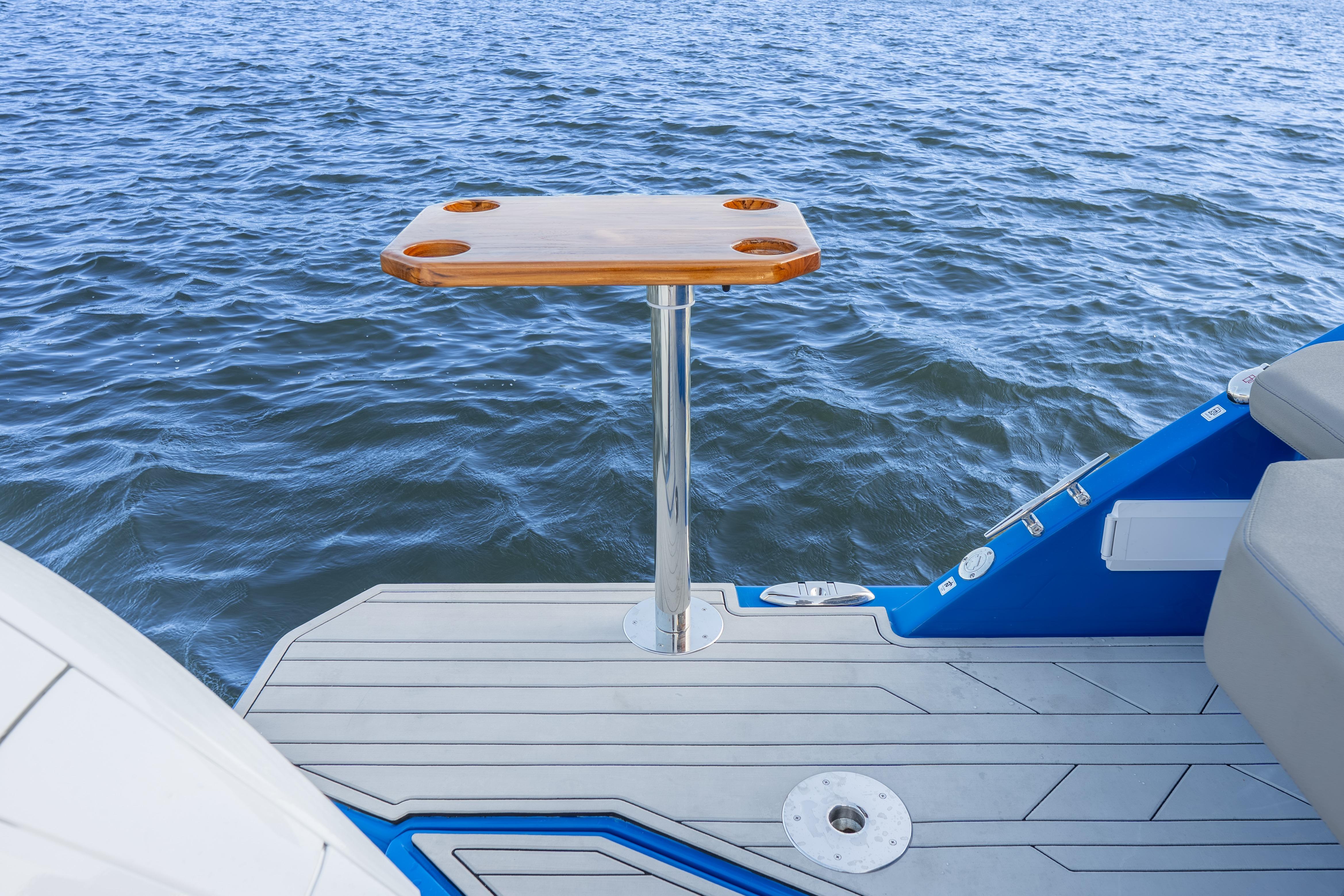 Luxury Hanover 347 boat deck with wooden table, 2026 model, overlooking serene water.