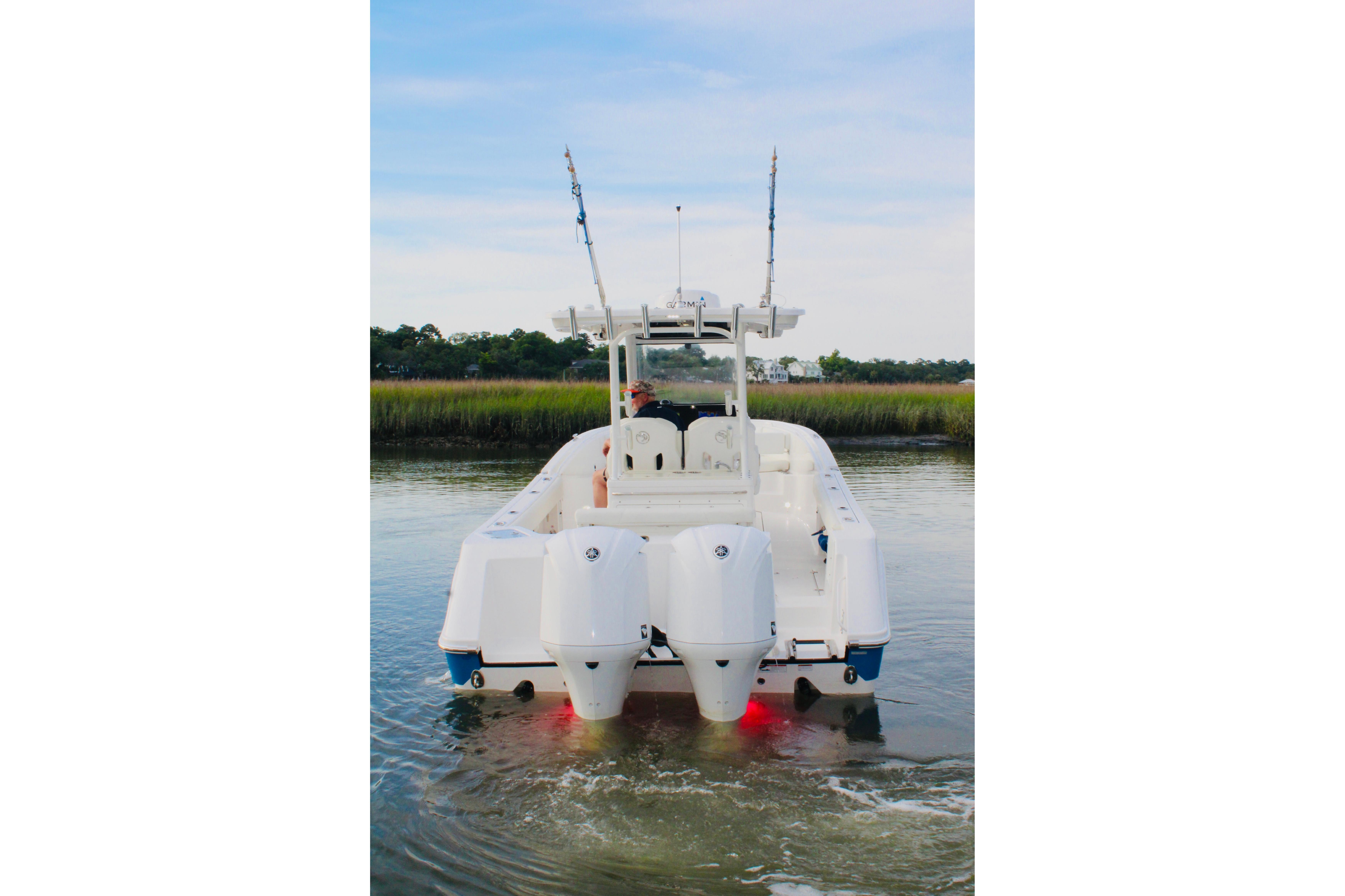 2022 Edgewater 280CC boat on water, rear view with dual engines and fishing rods.