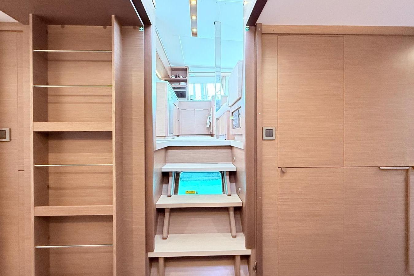 Interior of 2020 Lagoon 46 yacht with wooden stairs and shelving.