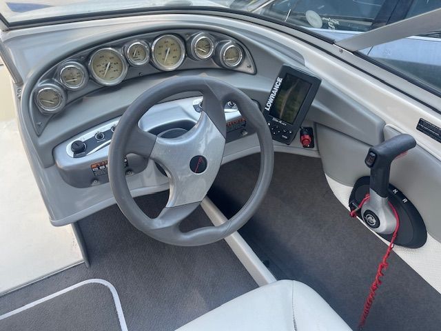 The cockpit of a Bayliner 185 boat with steering wheel and instrument panel.