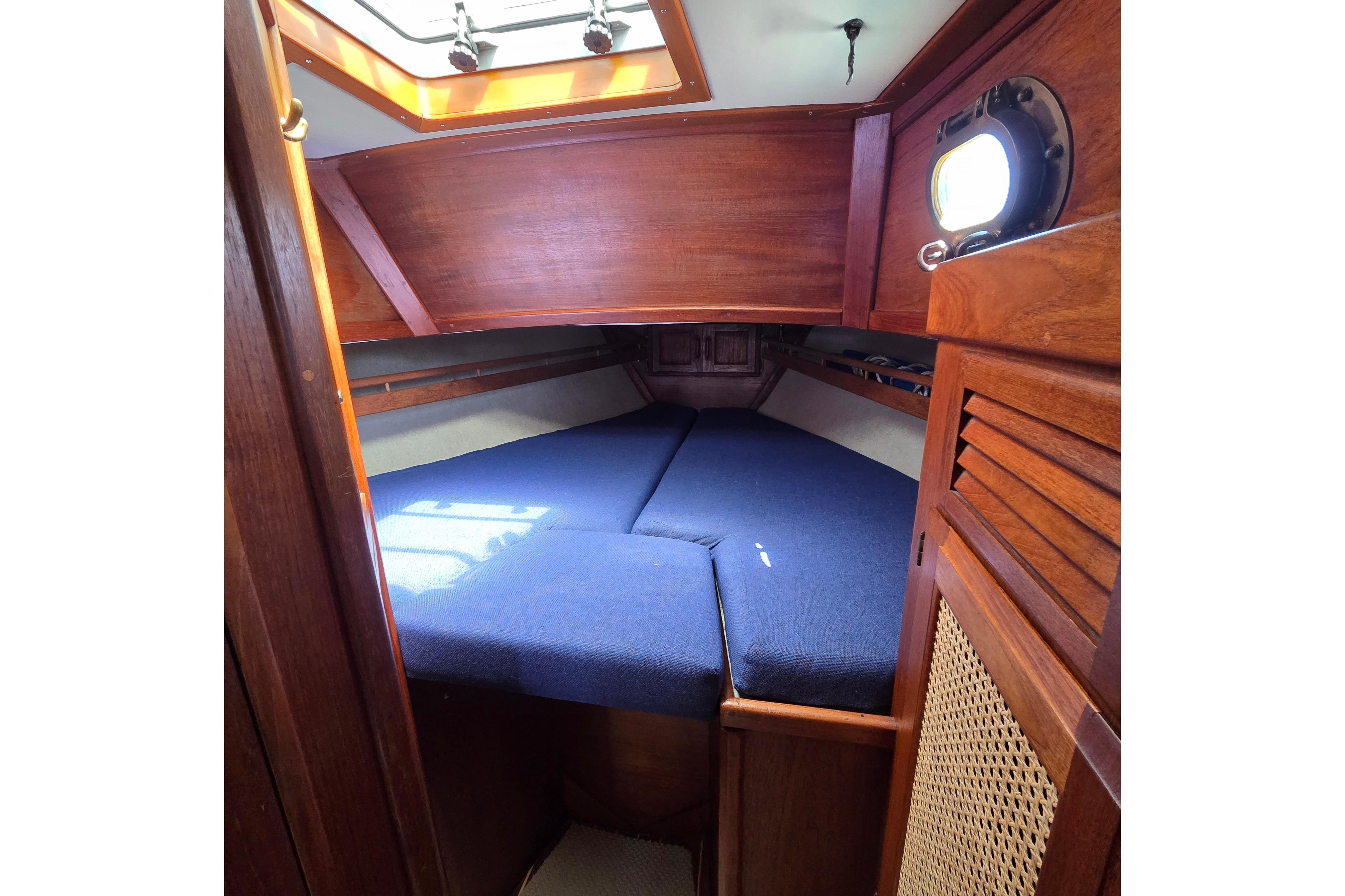Cozy cabin interior of 1983 Pacific Seacraft 34 sailboat with blue cushions and wooden finish.